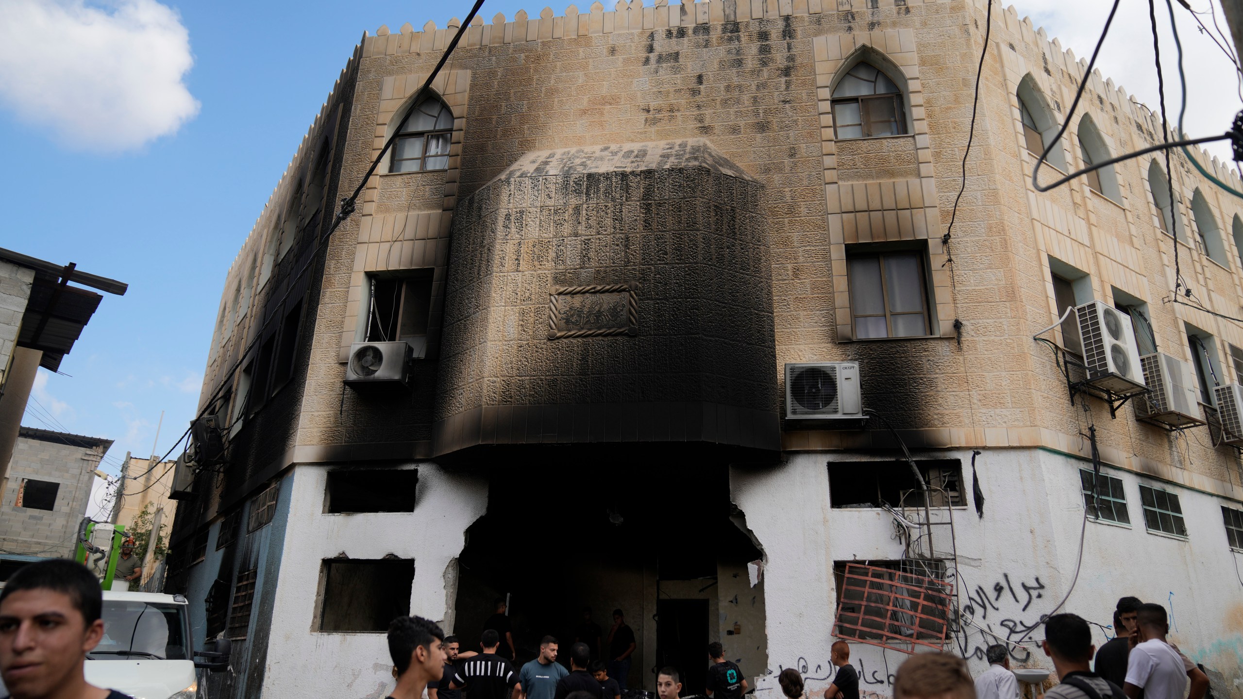 Palestinians stand outside a heavily damaged mosque following an Israeli military operation in the West Bank refugee camp of Al-Faraa, Thursday, Aug. 29, 2024. (AP Photo/Nasser Nasser)