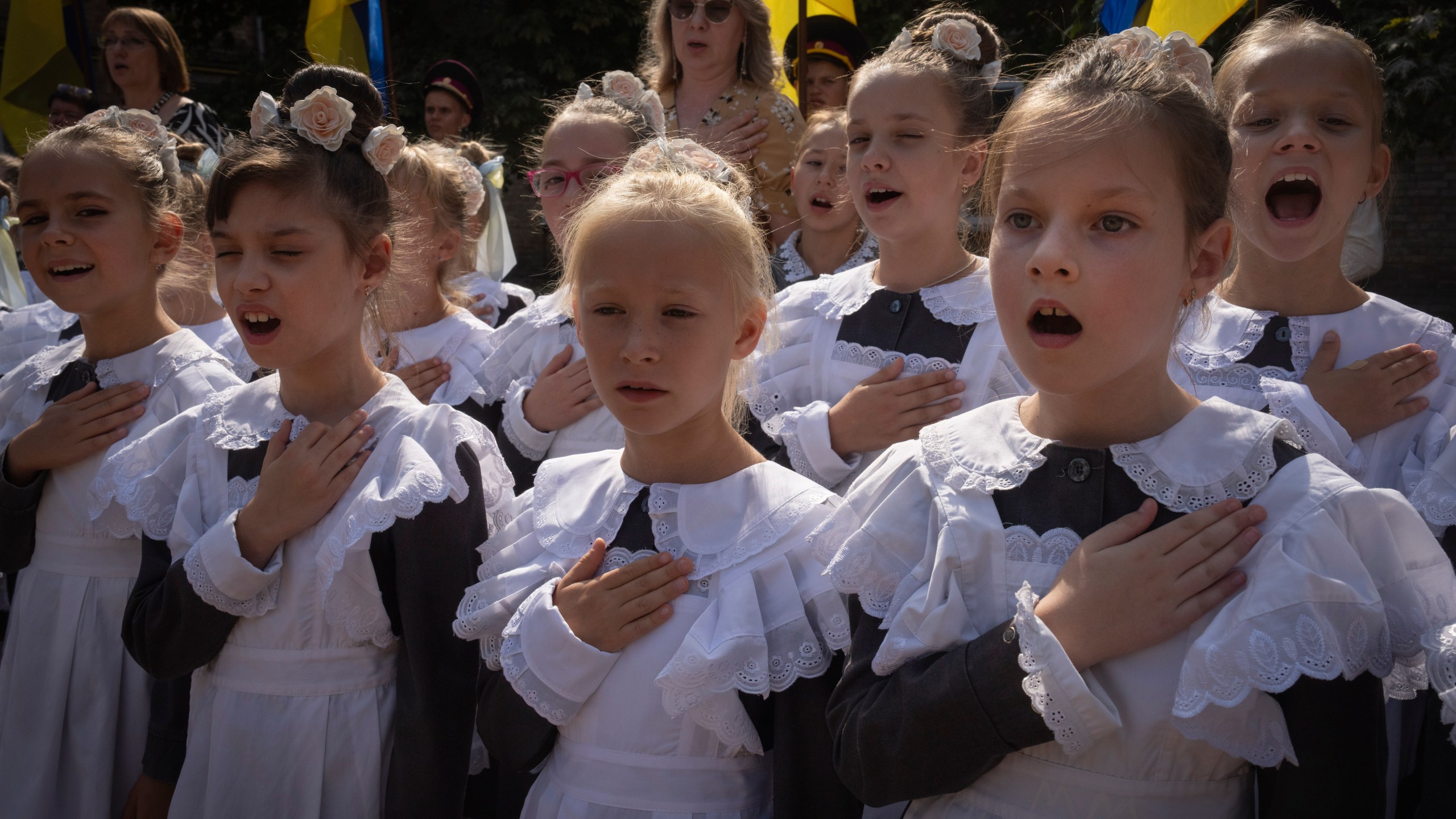 Schoolgirls sing the national anthem on the first day at school in a cadet lyceum in Kyiv, Ukraine, Monday, Sept. 2, 2024. Children and students went to school despite the fact that Kyiv was hit by massive Russian missile barrage early in the morning, causing fires, damaged buildings and infrastructure objects. (AP Photo/Efrem Lukatsky)