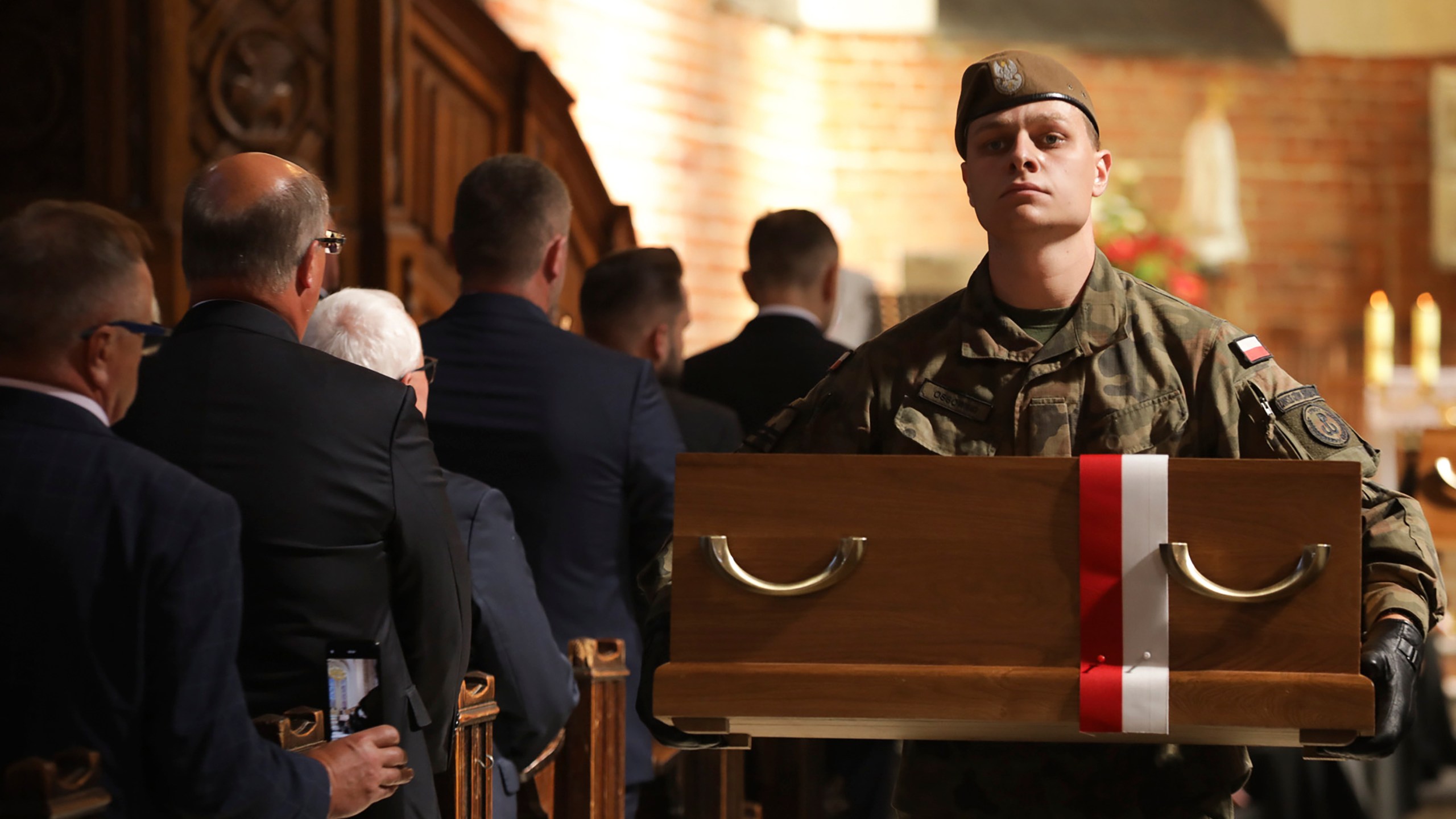 In this photo provided by Poland's Institute of National Remembrance, a soldier carries one of 188 coffins holding recently uncovered remains of more than 700 victims of Nazi Germany's World War II mass executions in northern Poland, during state burial ceremonies, in Chojnice, Poland, Monday, Sept. 2, 2024. (Mikołaj Bujak/Poland's Institute of National Remembrance, via AP)