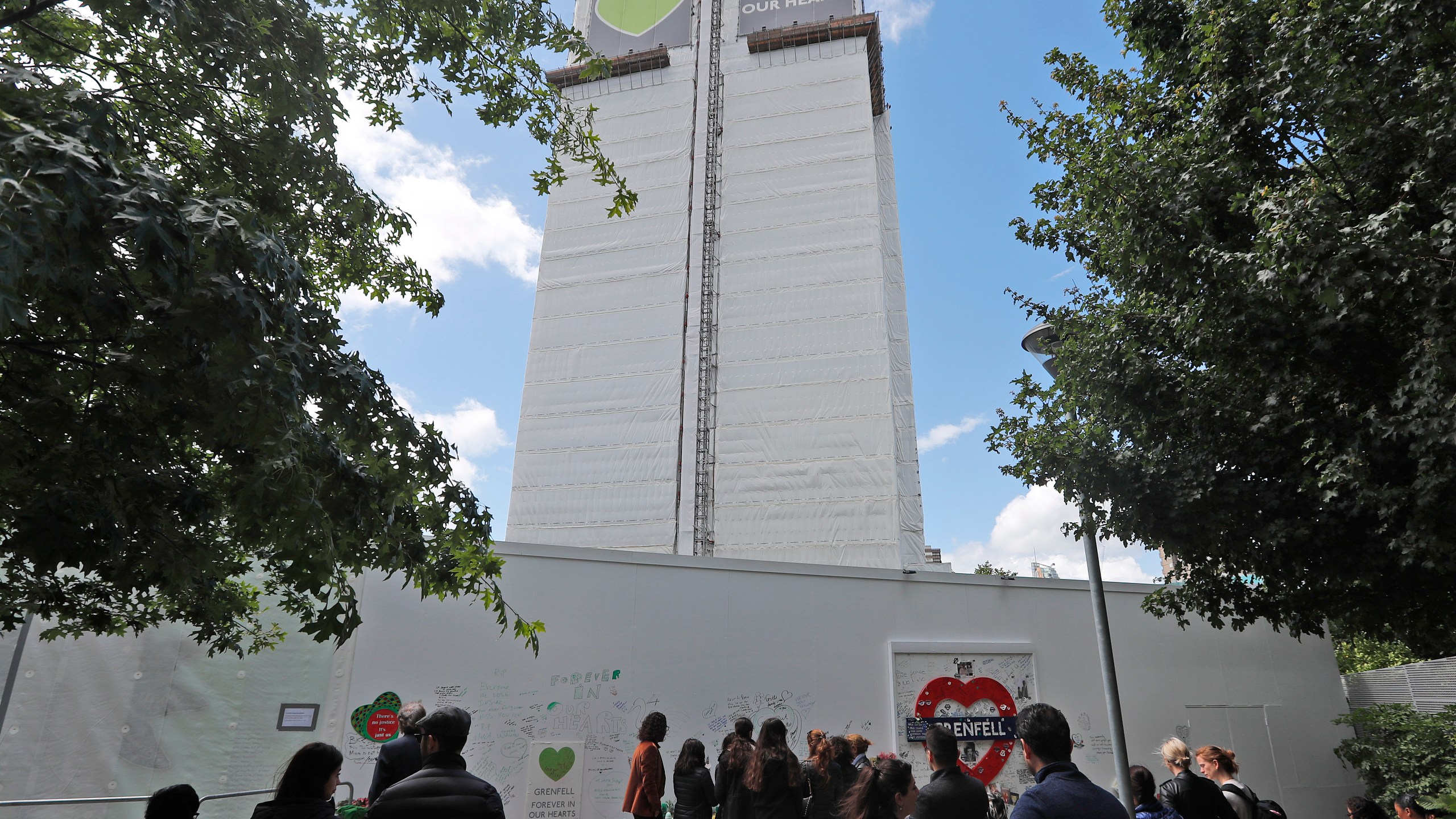 FILE - People pay their respects at the Grenfell tower to mark the two-year anniversary of the Grenfell Tower block fire, in London, Friday, June 14, 2019. (AP Photo/Frank Augstein, File)