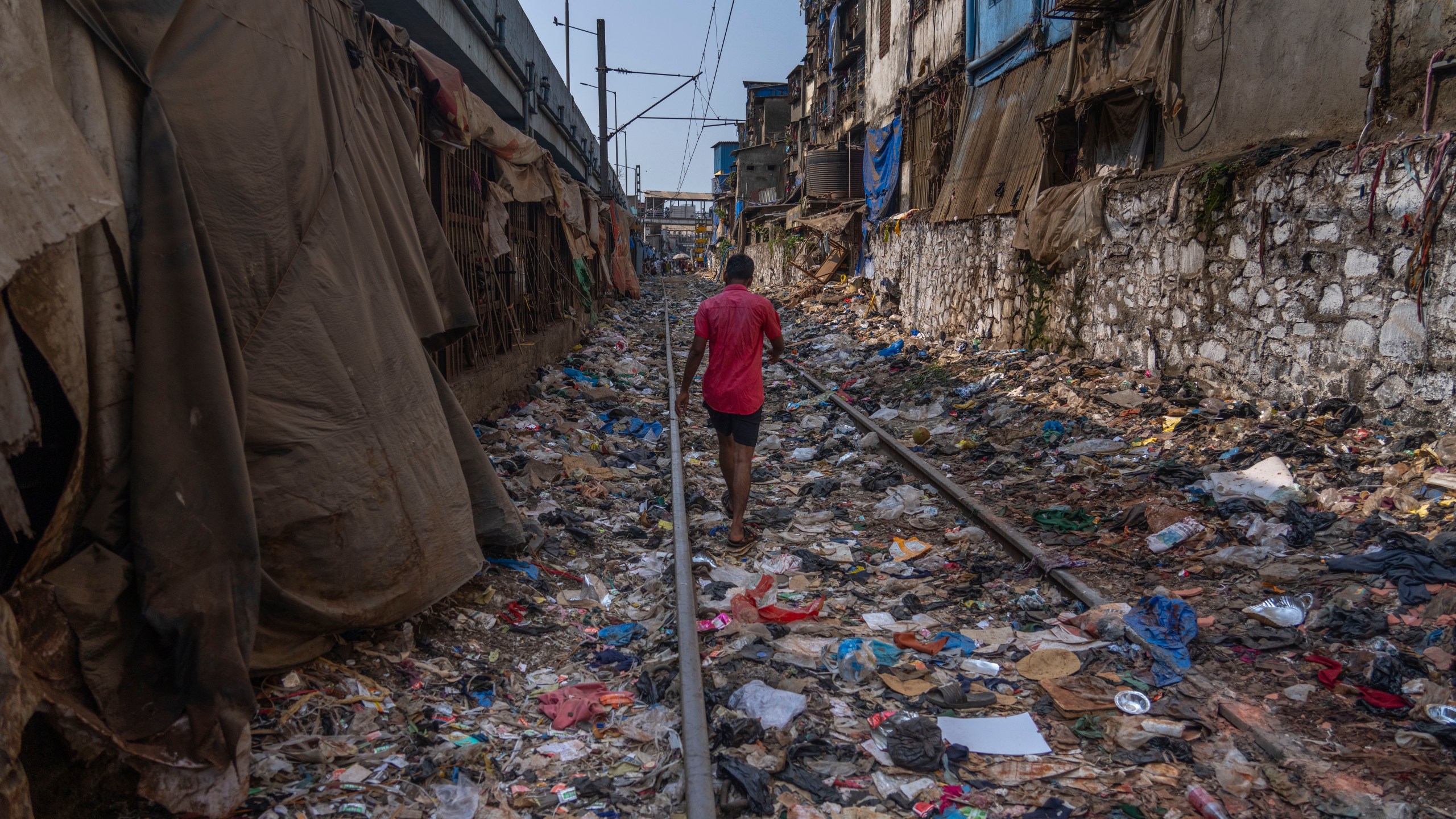 FILE - A man walks on a railway track littered with plastic and other waste materials on Earth Day in Mumbai, India, April 22, 2024. (AP Photo/Rafiq Maqbool, File)