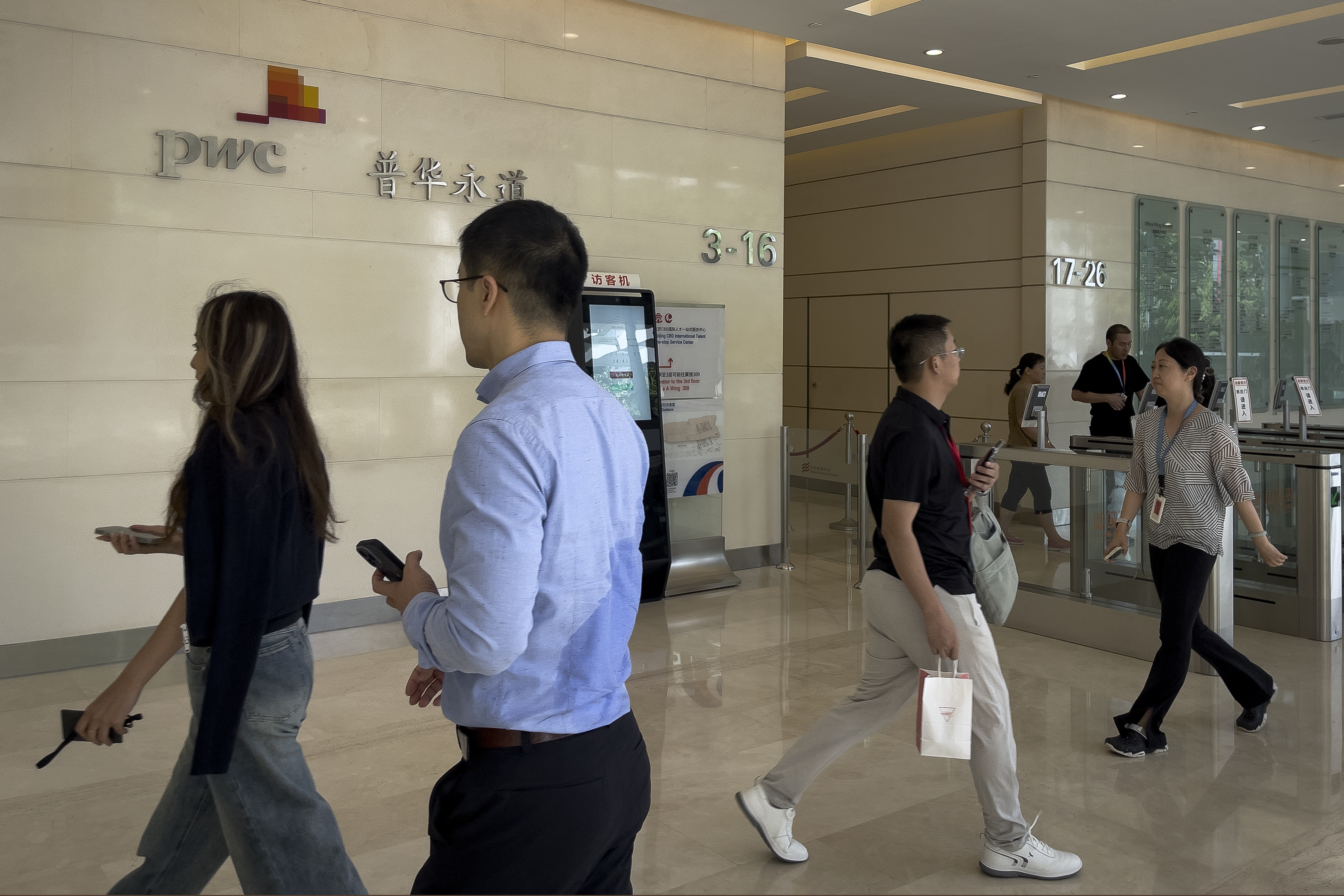 People walk by the audit firm PricewaterhouseCoopers (PWC) office at the Fortune Financial Center in Beijing on Aug. 27, 2024. (AP Photo/Andy Wong)