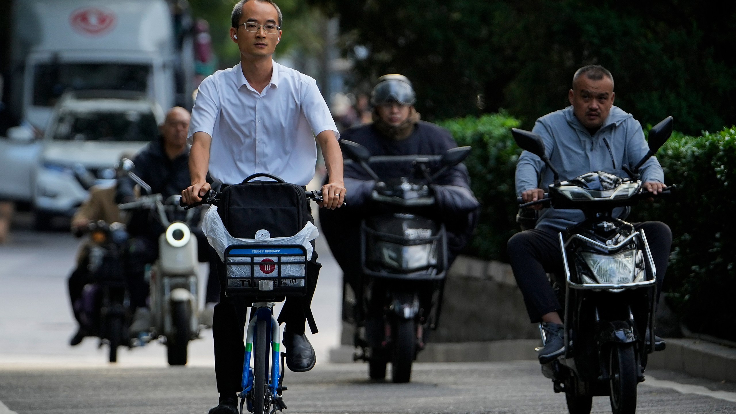 A man rides along motorists as they head to work during the morning rush hour in Beijing, Friday, Sept. 13, 2024. (AP Photo/Andy Wong)