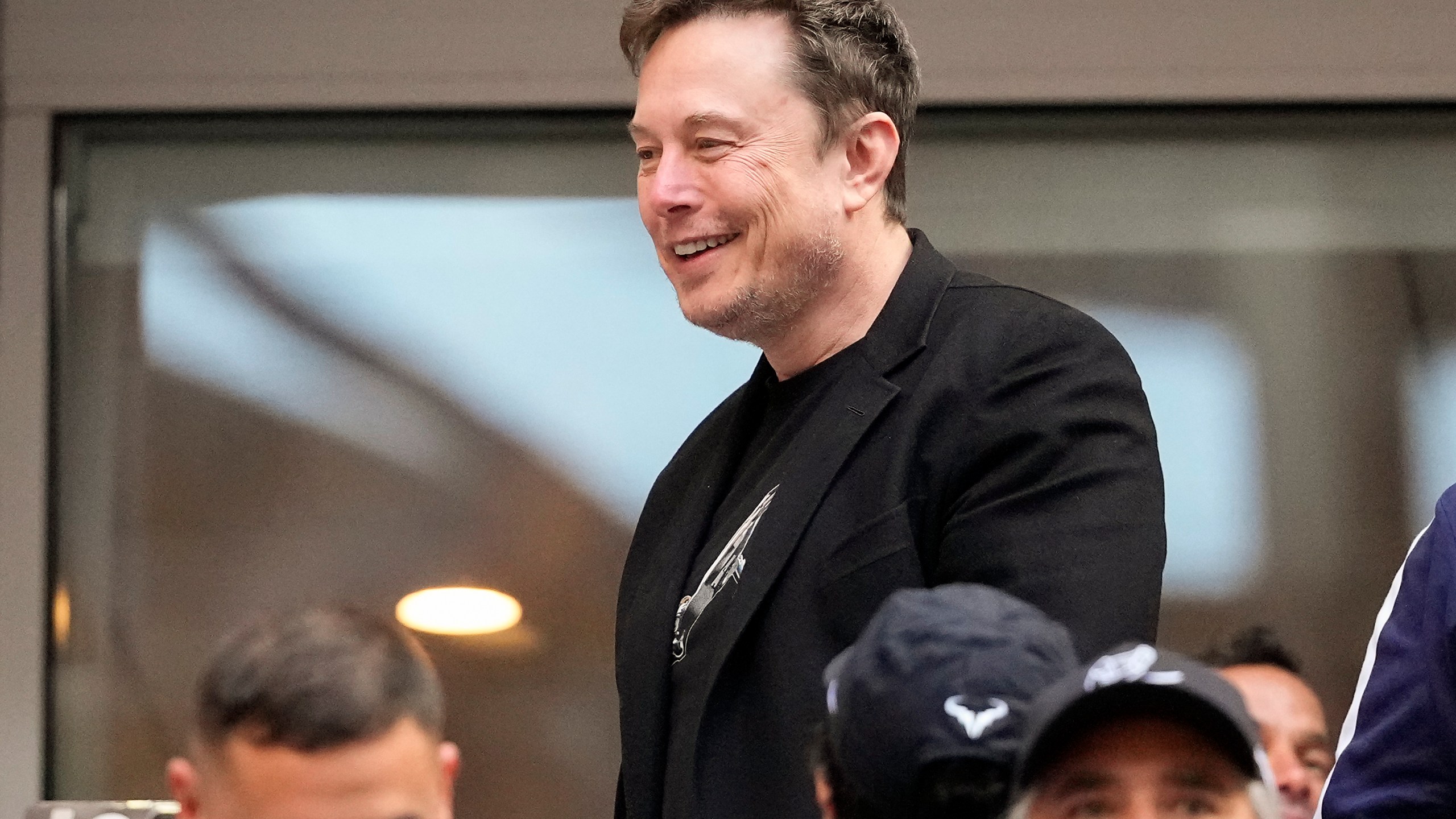 Elon Musk talks to other spectators while watching play between Jannik Sinner, of Italy, and Taylor Fritz, of the United States, during the men's singles final of the U.S. Open tennis championships, Sunday, Sept. 8, 2024, in New York. (AP Photo/Kirsty Wigglesworth)