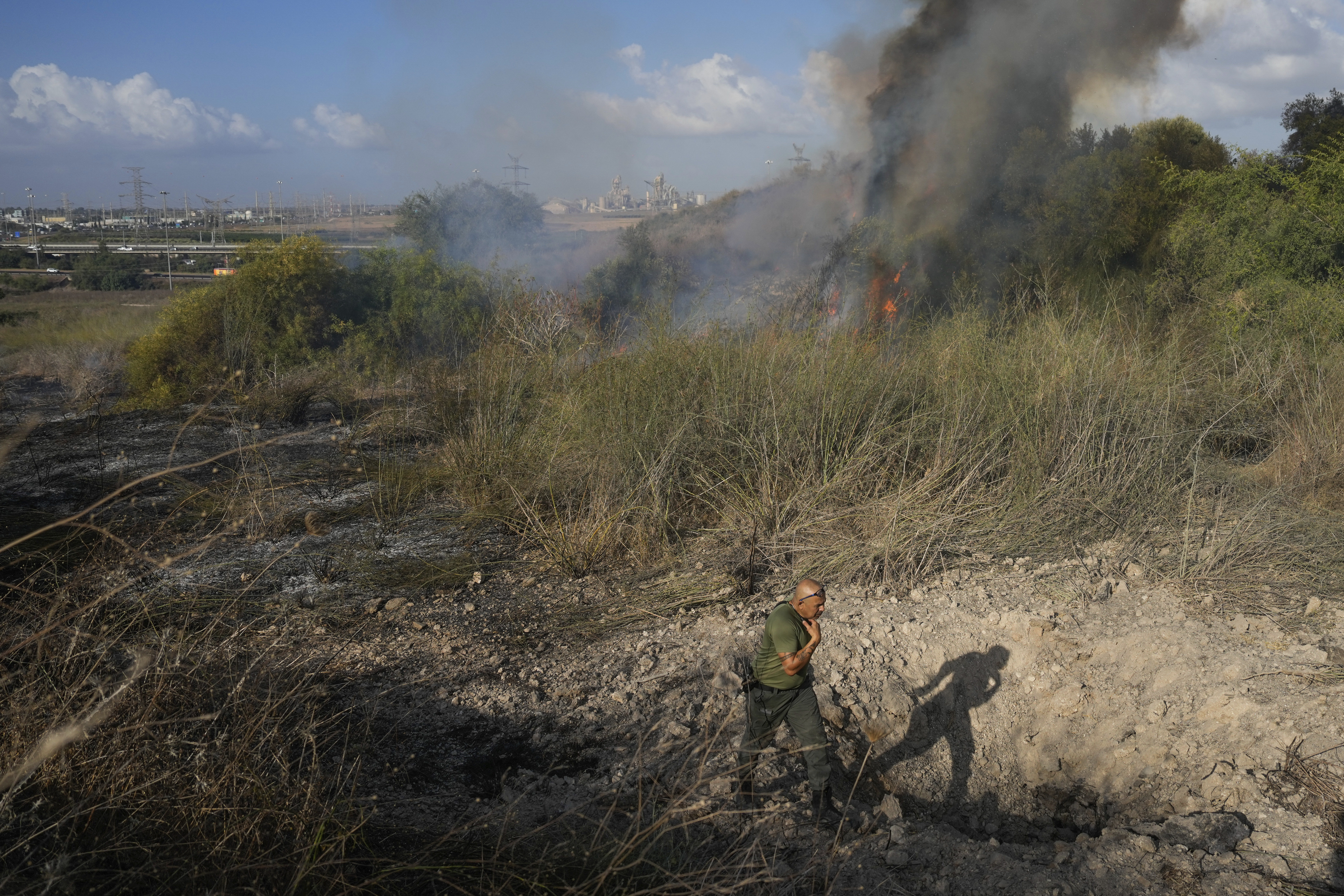 A police officer inspects the area around a fire after the military said it fired interceptors at a missile launched from Yemen that landed in central Israel on Sunday, Sept. 15, 2024. (AP Photo/Ohad Zwigenberg)