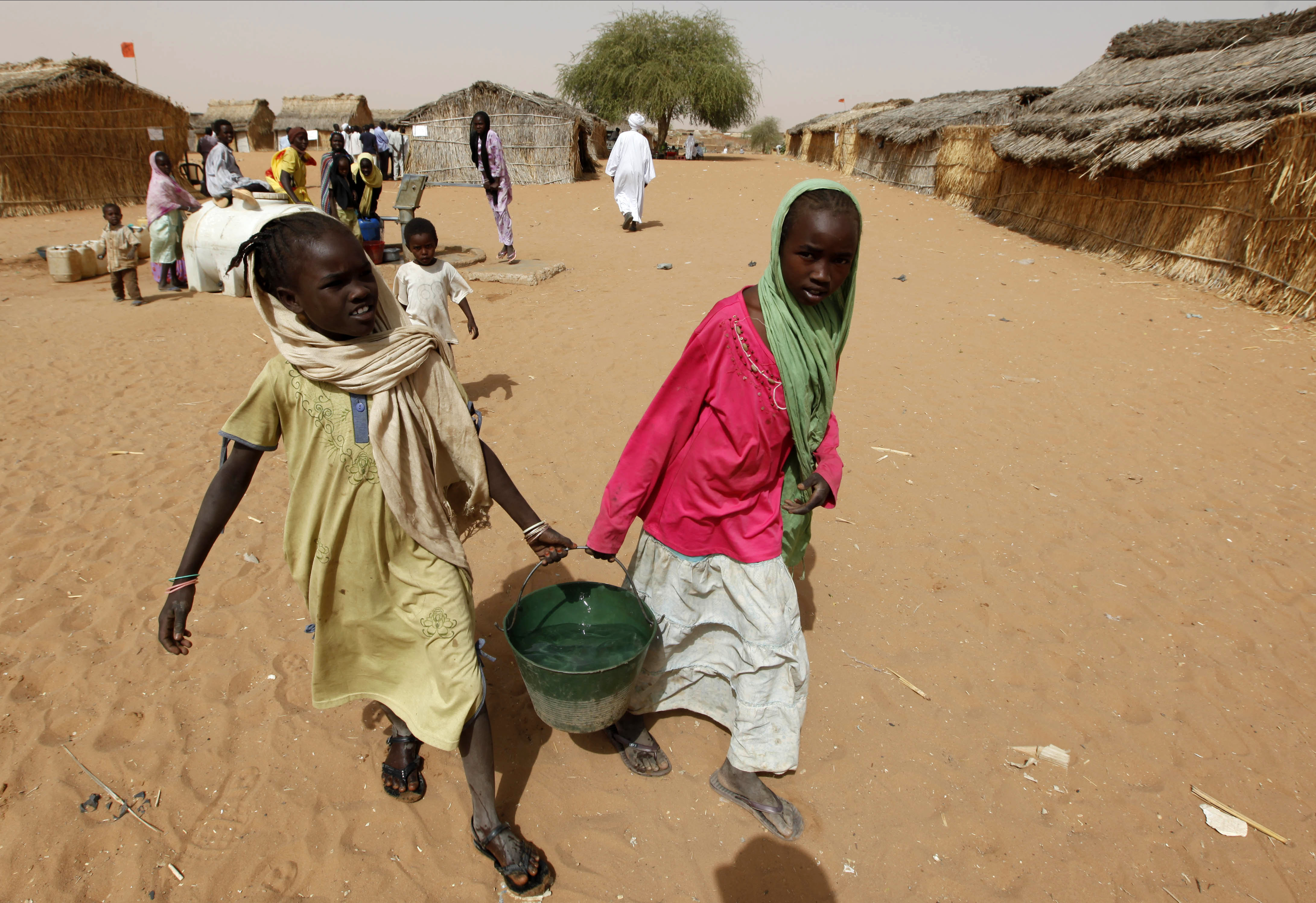 FILE - Sudanese refugee girls carry water supplies near a polling station in the refugee camp of Zamzam, on the outskirts of El Fasher, Darfur, Sudan, on April 13, 2010. (AP Photo/Nasser Nasser, File)