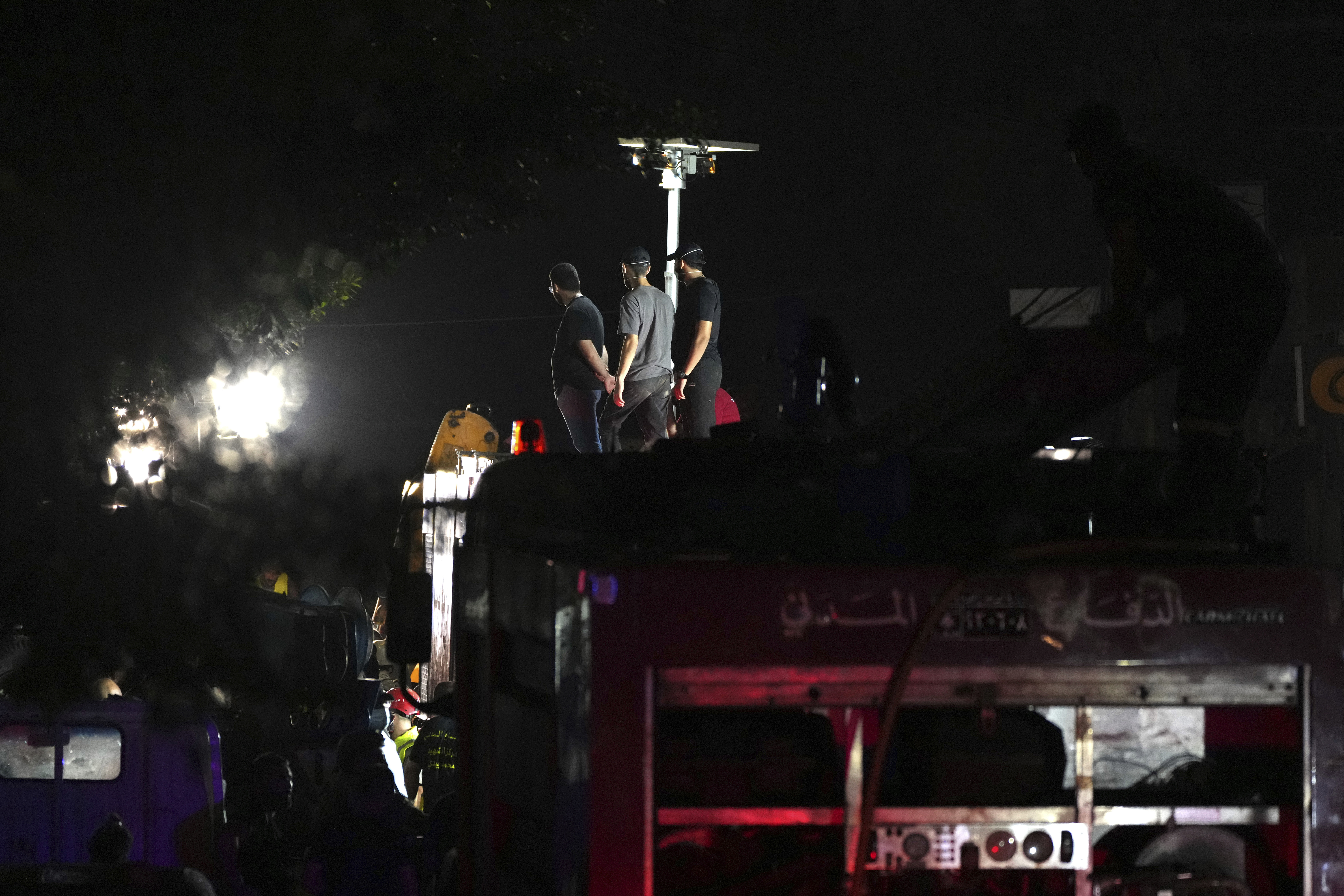 Members of Hezbollah stand on a fire truck as rescuers work at the scene of an Israeli missile strike in the southern suburbs of Beirut, Friday, Sept. 20, 2024. (AP Photo/Hassan Ammar)