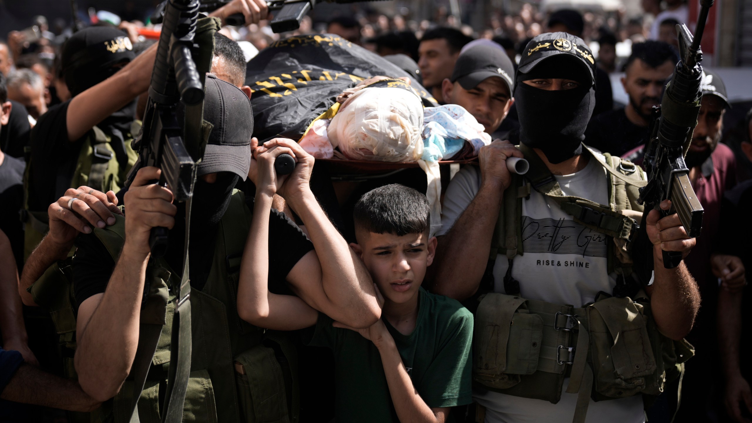 Gunmen march with the body of Mustafa Zakarneh, draped the Islamic Jihad militant flag during the funeral for three Palestinian militants killed in an Israeli military operation in the West Bank town of Qabatiya, Friday, Sept. 20, 2024. (AP Photo/Majdi Mohammed)