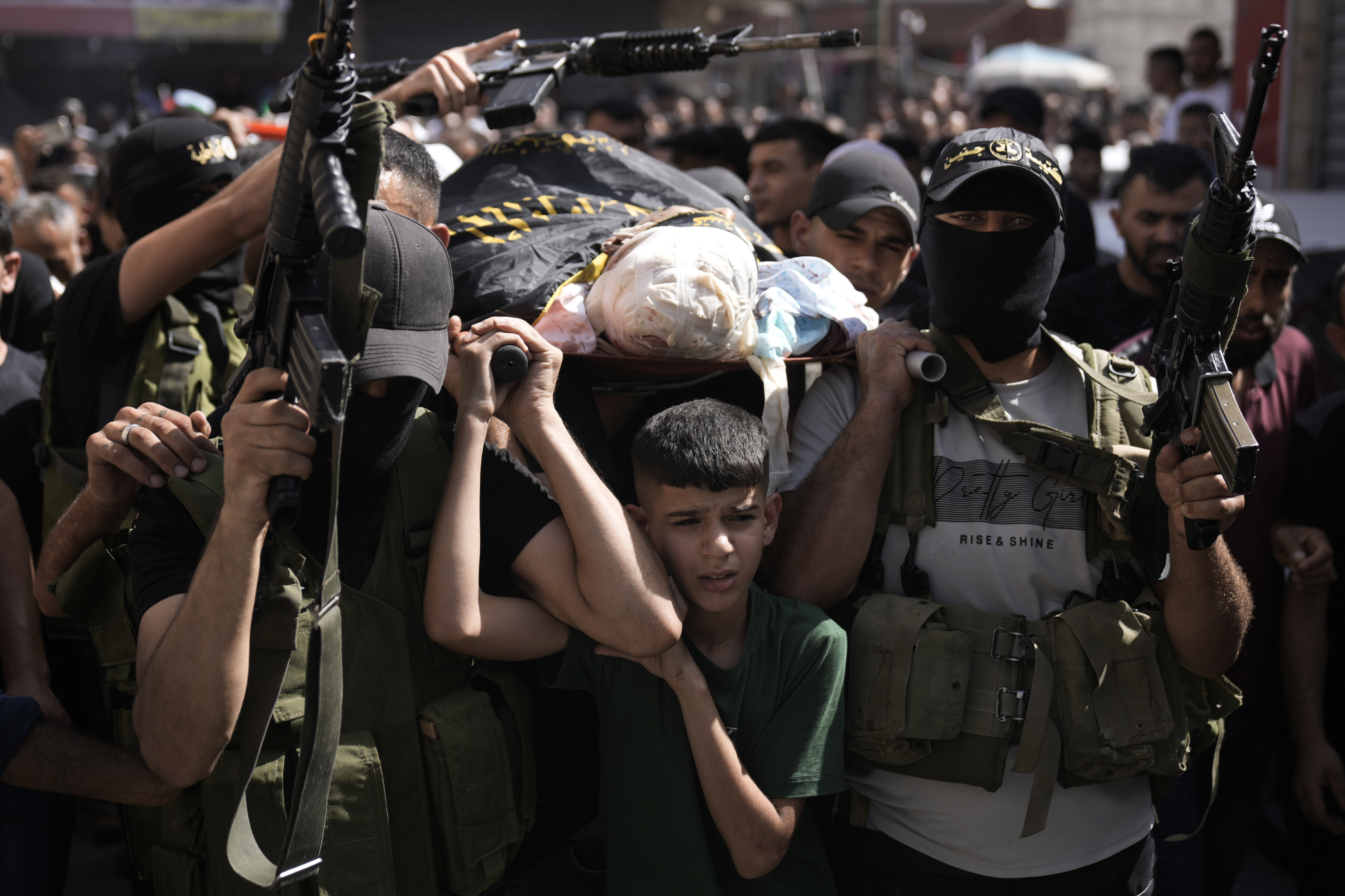 Gunmen march with the body of Mustafa Zakarneh, draped the Islamic Jihad militant flag during the funeral for three Palestinian militants killed in an Israeli military operation in the West Bank town of Qabatiya, Friday, Sept. 20, 2024. (AP Photo/Majdi Mohammed)