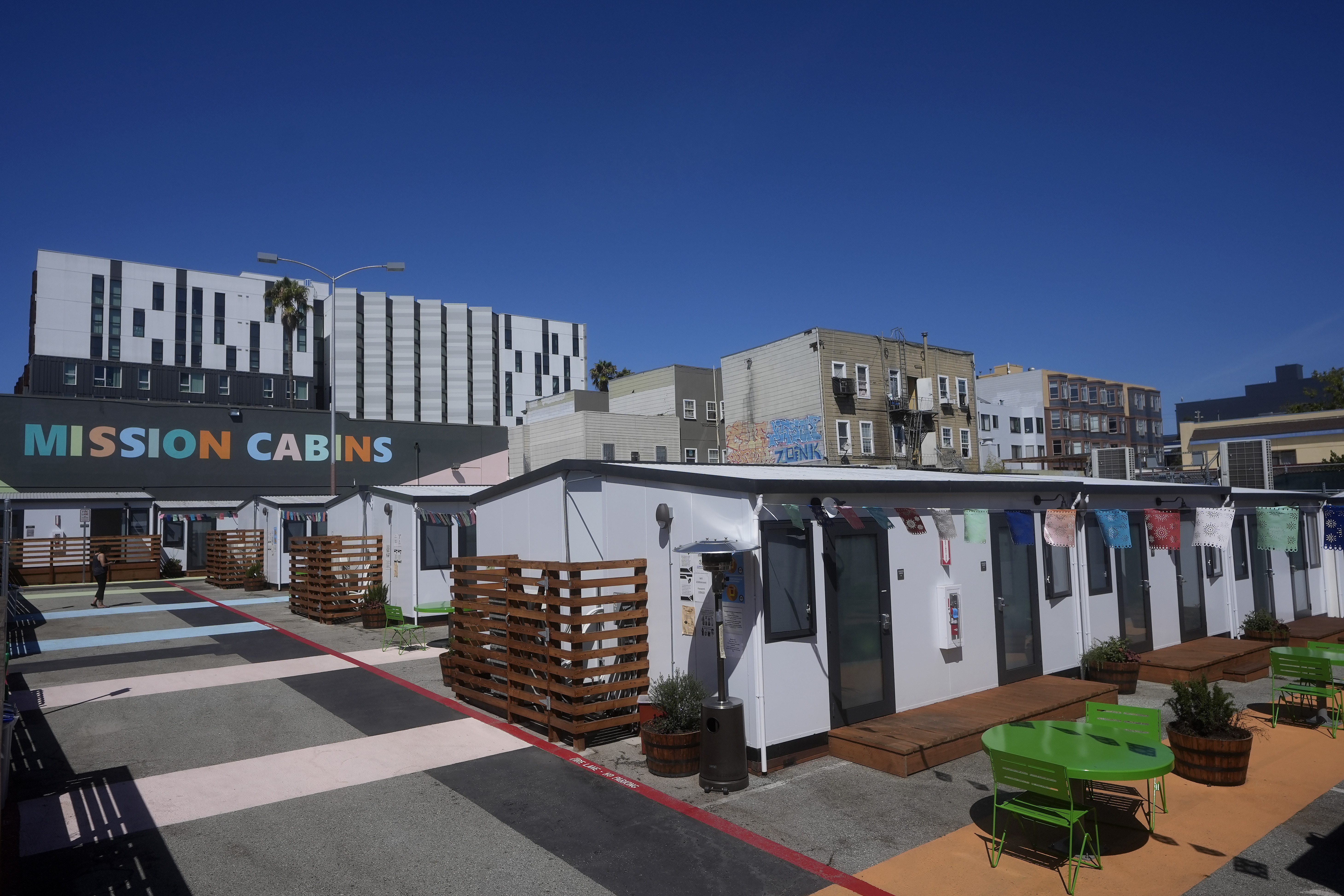 A person walks under a Mission Cabins sign at the Five Keys transitional housing location in San Francisco, Monday, Aug. 26, 2024. (AP Photo/Jeff Chiu)