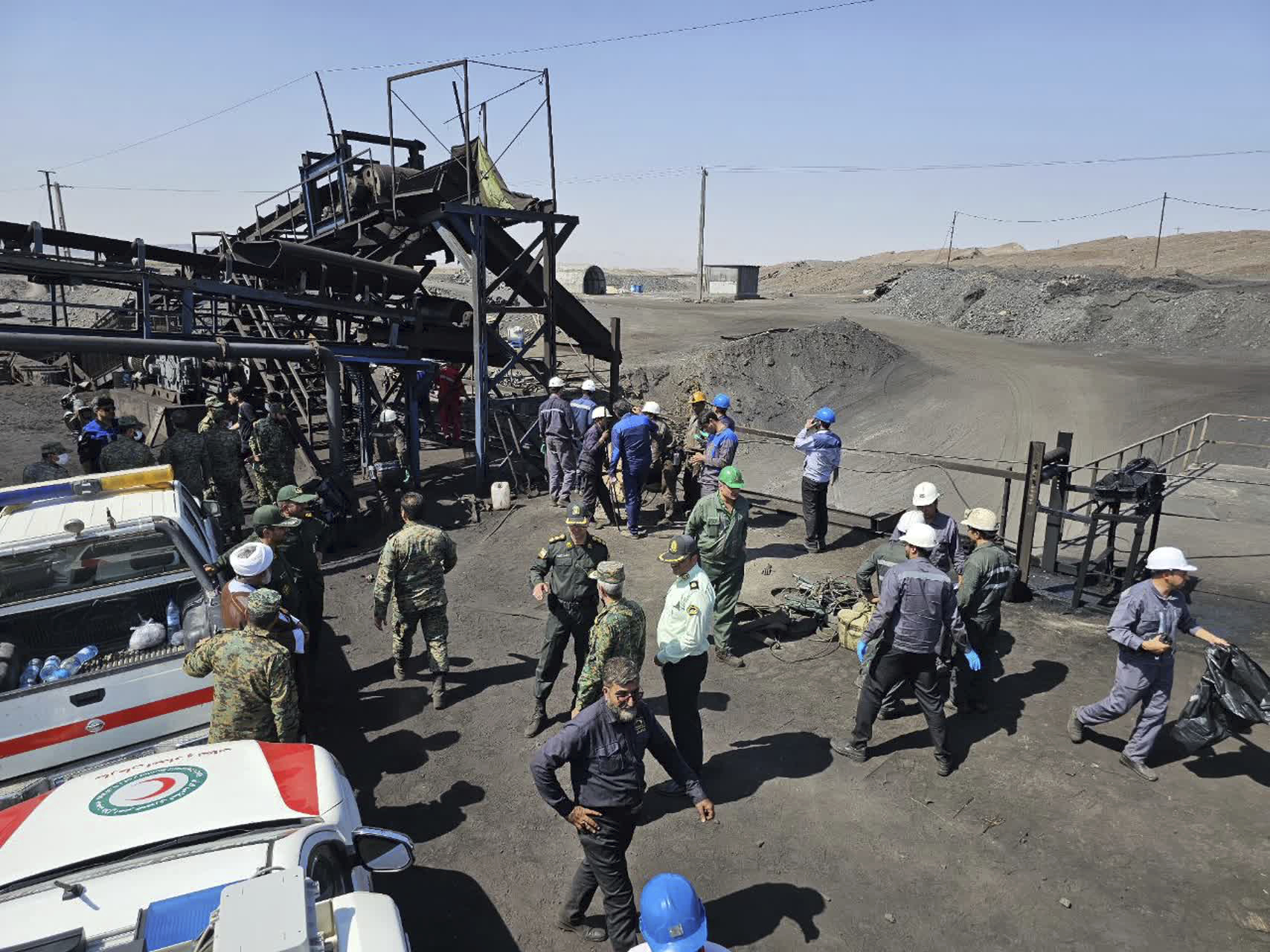 In this photo released by Iranian Red Crescent Society, miners and police officers are seen at the site of a coal mine where methane leak sparked an explosion on Saturday, in Tabas, some 540 kilometers (335 miles) southeastern of the capital, Tehran, Iran, Sunday, Sept. 22, 2024. (Iranian Red Crescent Society, via AP)