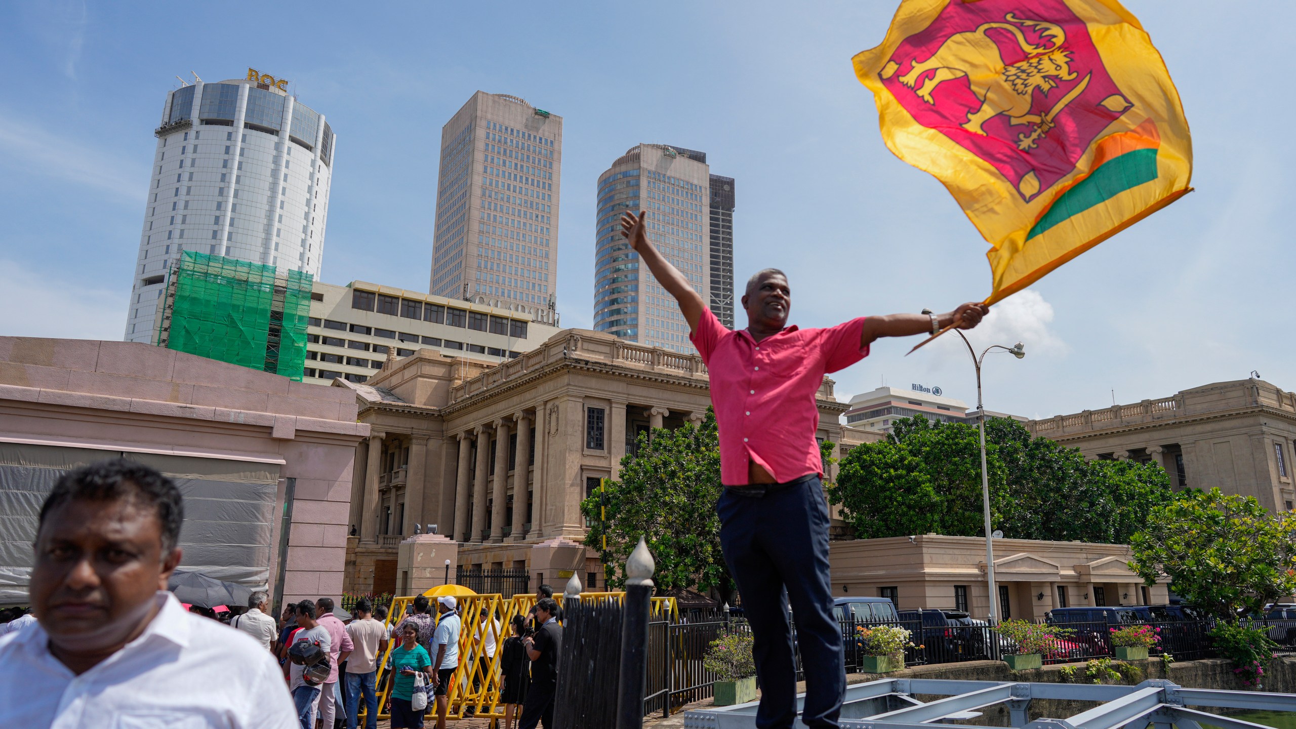 A supporter waves Sri Lankan flag as he waits for the swearing in ceremony of president elect Marxist lawmaker Anura Kumara Dissanayake out side president's office in Colombo, Sri Lanka, Monday, Sept. 23, 2024. (AP Photo/Eranga Jayawardena)