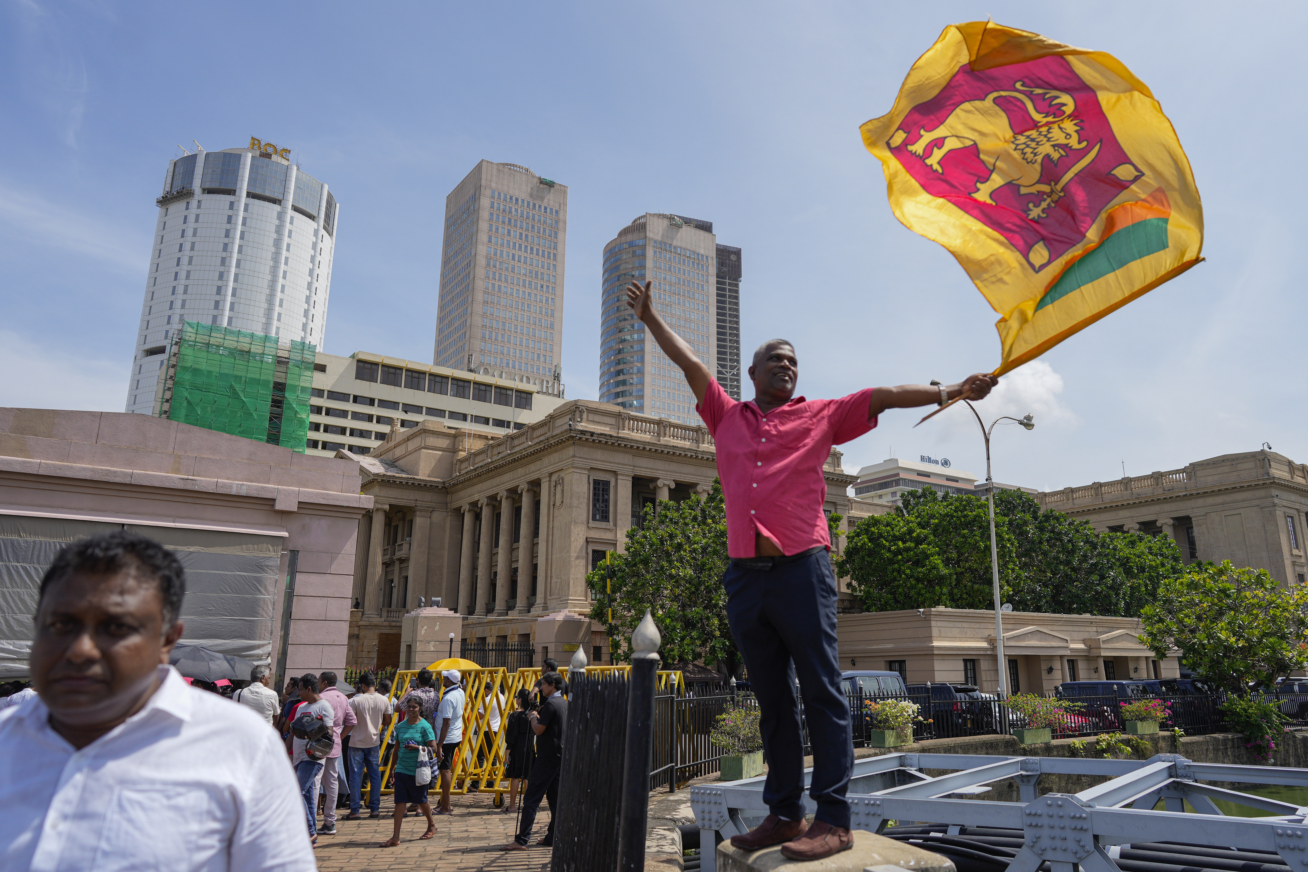 A supporter waves Sri Lankan flag as he waits for the swearing in ceremony of president elect Marxist lawmaker Anura Kumara Dissanayake out side president's office in Colombo, Sri Lanka, Monday, Sept. 23, 2024. (AP Photo/Eranga Jayawardena)