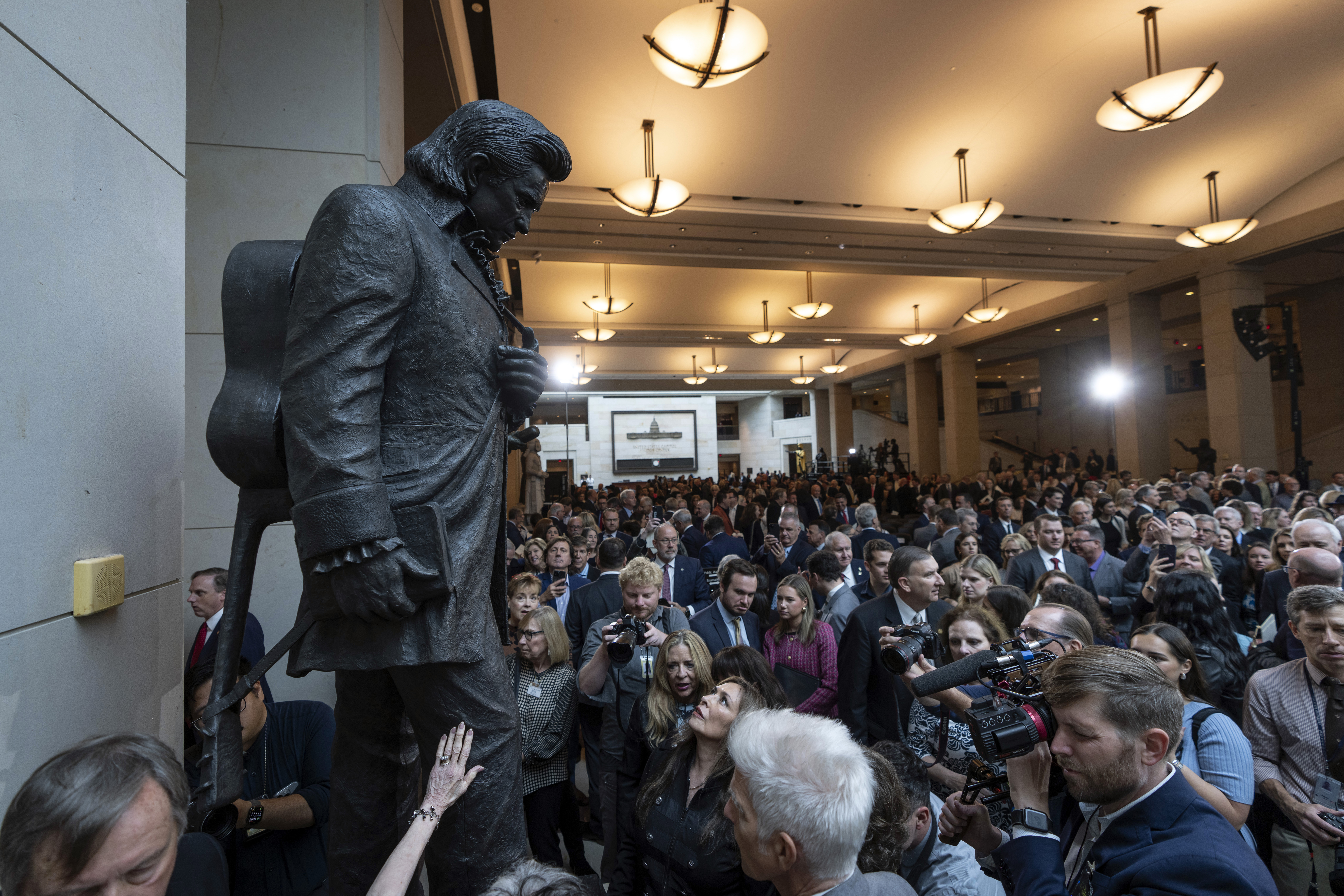 People crowd around after the unveiling of a bronze statue of singer Johnny Cash, created by Little Rock sculptor Kevin Kresse, in Emancipation Hall at the Capitol in Washington, Tuesday, Sept. 24, 2024. (AP Photo/Ben Curtis)