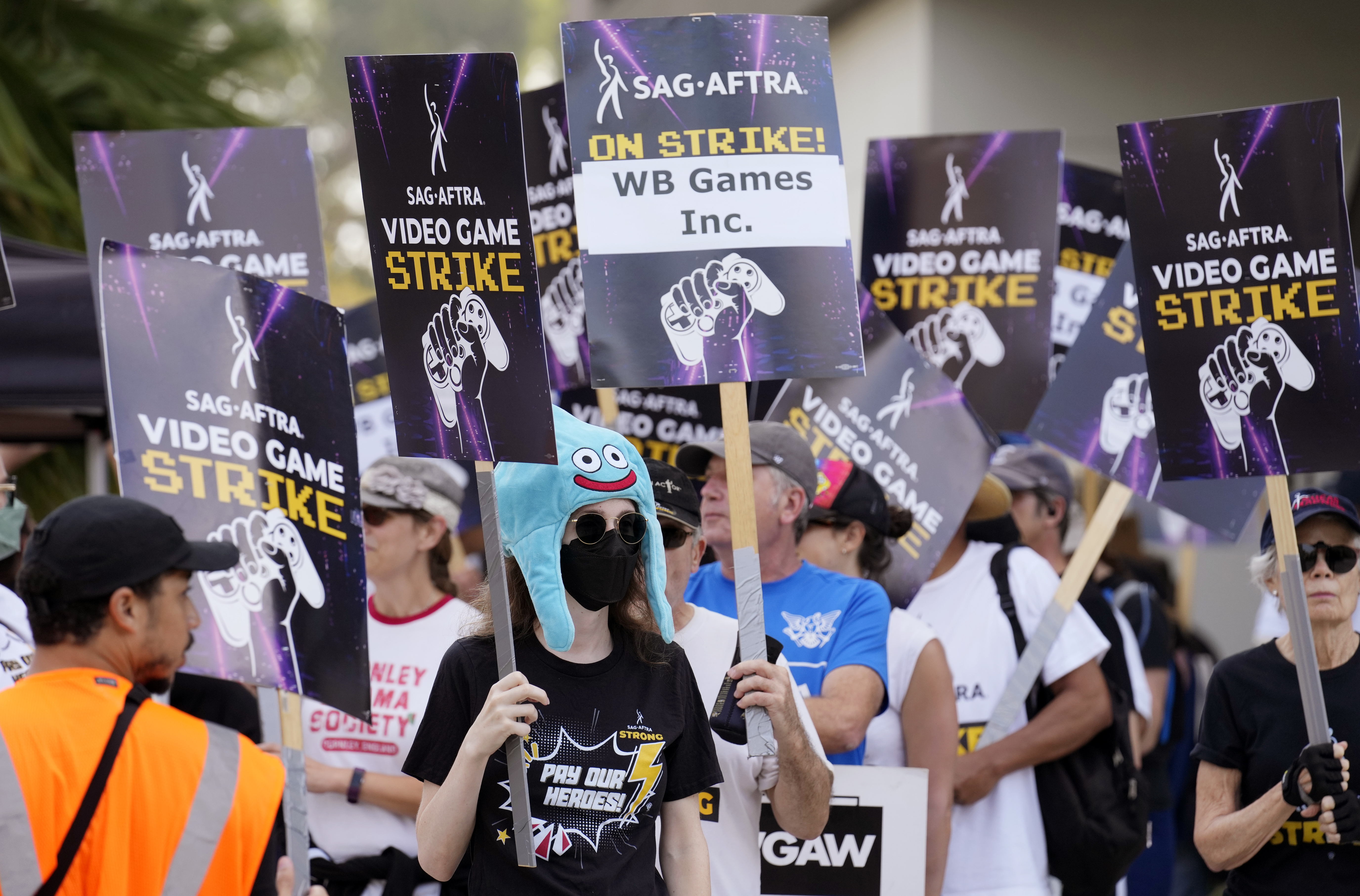 Actor Sena Bryer, second from left, joins other demonstrators in a SAG-AFTRA video game actor strike picket line outside Warner Bros. Studios on Wednesday, Aug. 28, 2024, in Burbank, Calif. (AP Photo/Chris Pizzello)