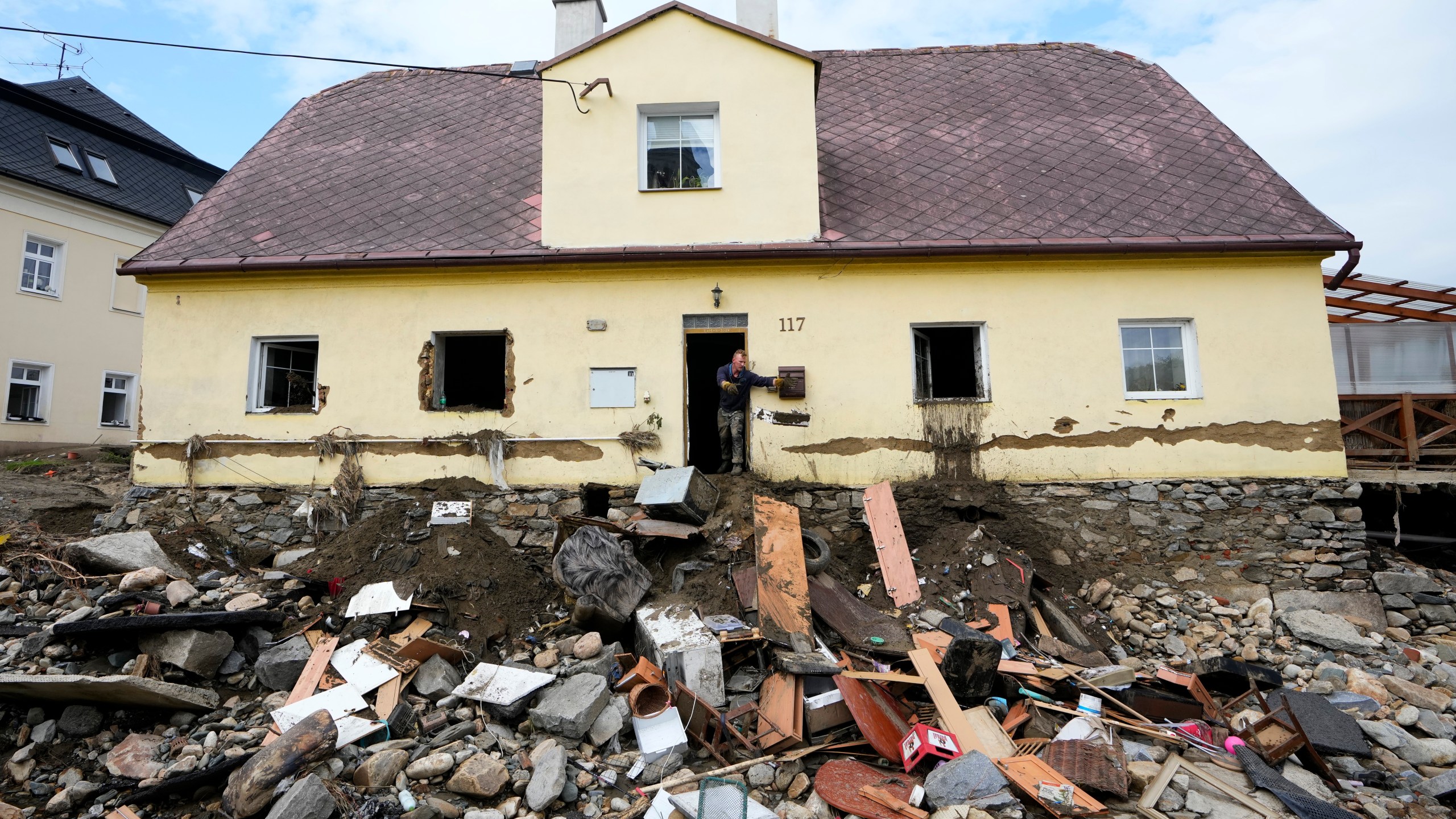 FILE - A man throws damaged goods and furniture off a house as residents return to clean up after recent floods in Mikulovice, Czech Republic, Sept. 19, 2024. (AP Photo/Petr David Josek, File)