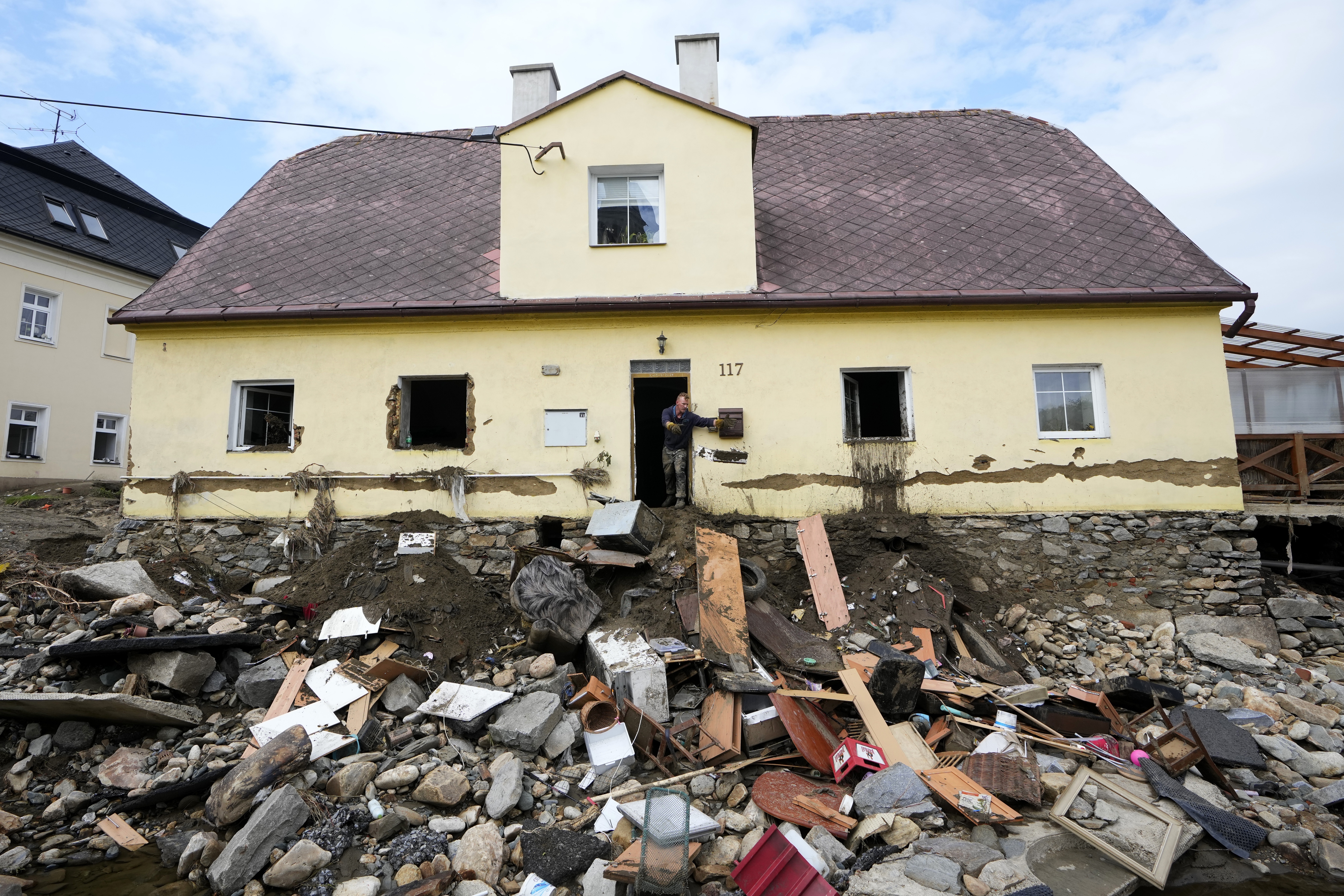 FILE - A man throws damaged goods and furniture off a house as residents return to clean up after recent floods in Mikulovice, Czech Republic, Sept. 19, 2024. (AP Photo/Petr David Josek, File)