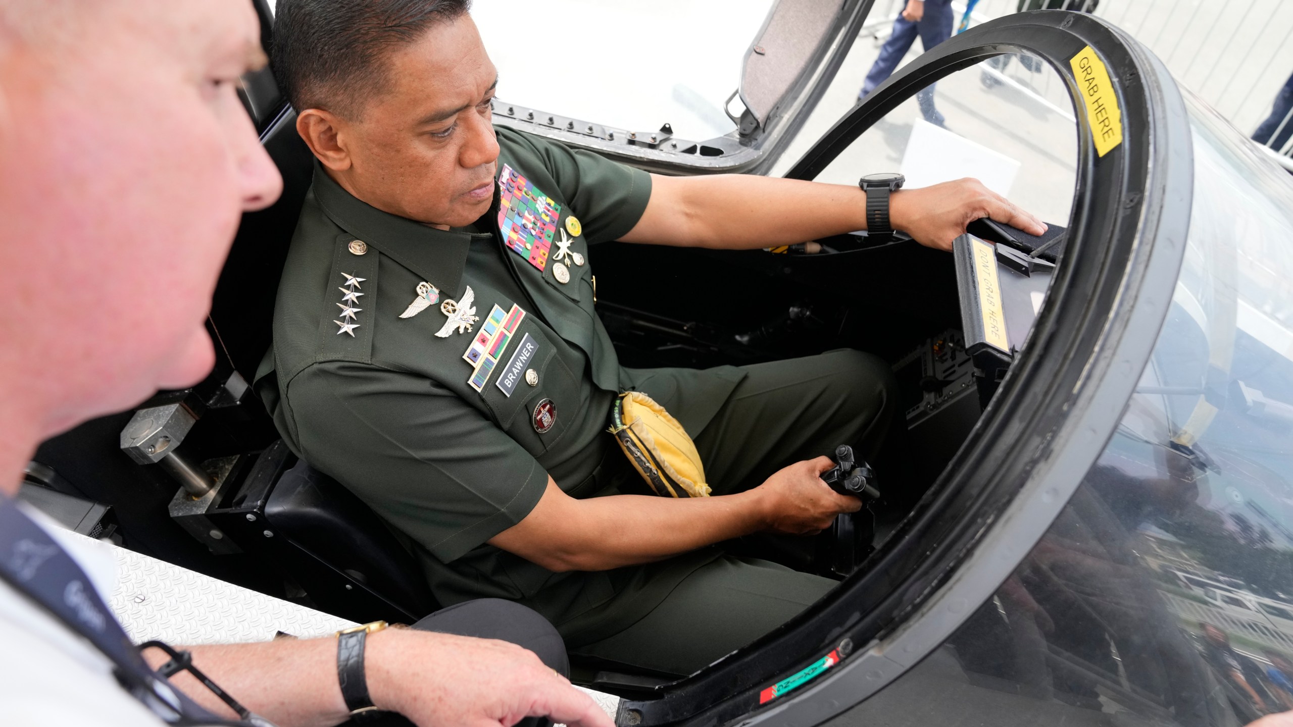 Philippine military chief Gen. Romeo Brawner Jr. right, sits inside the cockpit of a replica of a Saab Gripen combat aircraft during the Asian Defense and Security Exhibition on Wednesday, Sept. 25, 2024, in Manila, Philippines. (AP Photo/Aaron Favila)