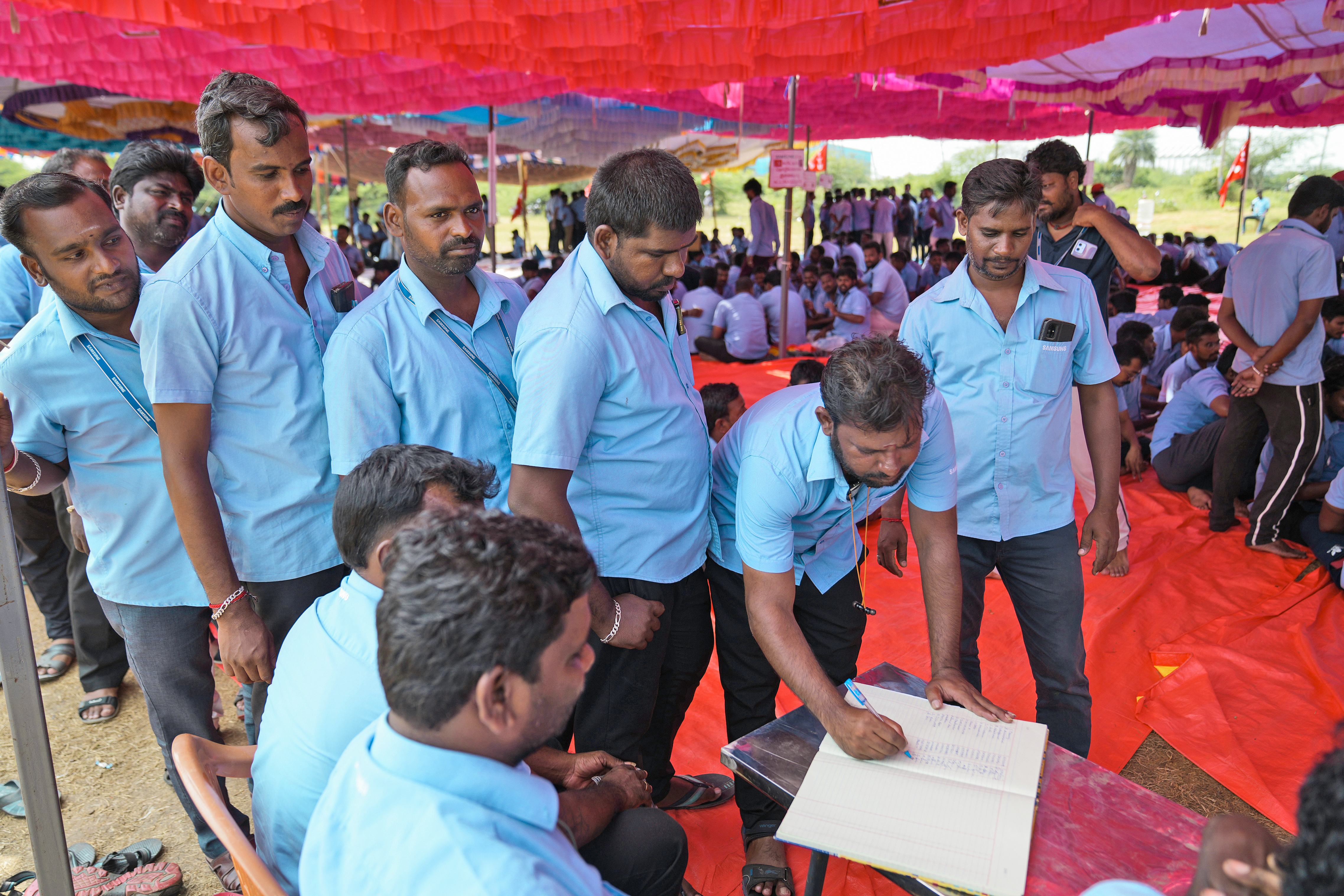 Samsung workers who are on strike sign a register as they arrive for a protest near their plant in Sriperumbudur, on the outskirts of Chennai, India, Tuesday, Sept. 24, 2024. (AP Photo/Mahesh Kumar A.)