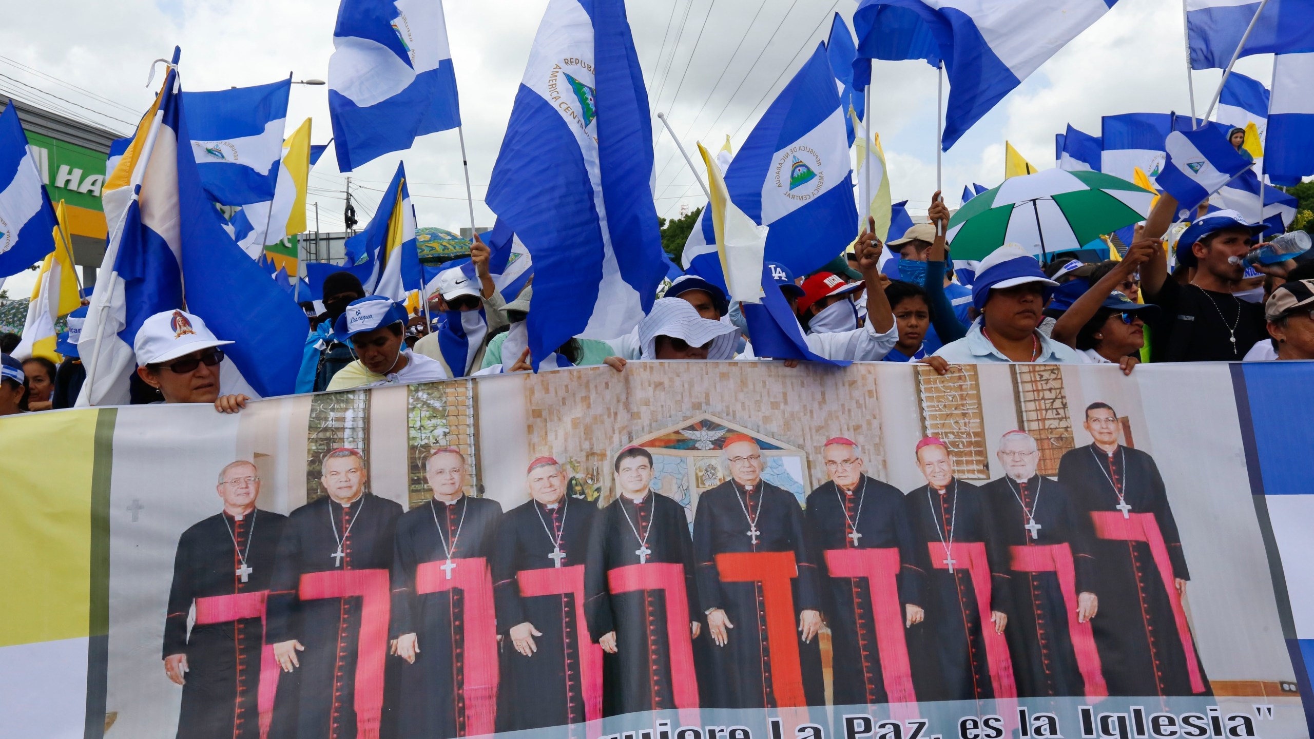 FILE - Anti-government demonstrators hold a banner featuring a group of Catholic cardinals including Nicaraguan Leopoldo Brenes, center right, and a quote from John Paul II that reads in Spanish, "The Church is the first to want peace!", during a march supporting the Catholic Church, in Managua, Nicaragua, July 28, 2018. (AP Photo/Alfredo Zuniga, File)