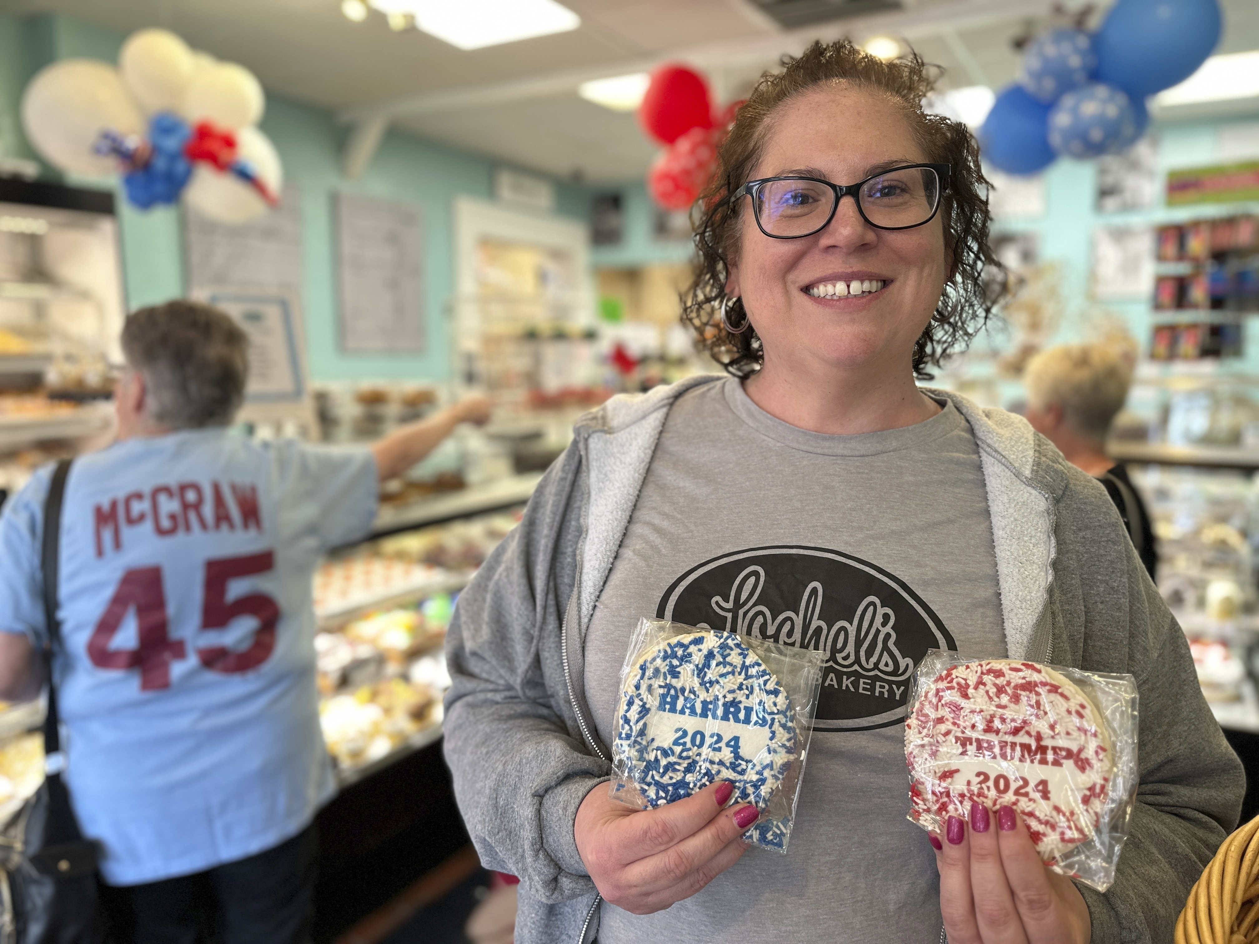 Bakery owner Kathleen Lochel holds sugar cookies, one with blue and white sprinkles and a Harris 2024 label on it and the other, with red and white sprinkles and a Trump 2024 label on it in Lochel Bakery, Tuesday, Sept. 24, 2024, in Hatboro, a suburb of Philadelphia. (AP Photo/Tassanee Vejpongsa)