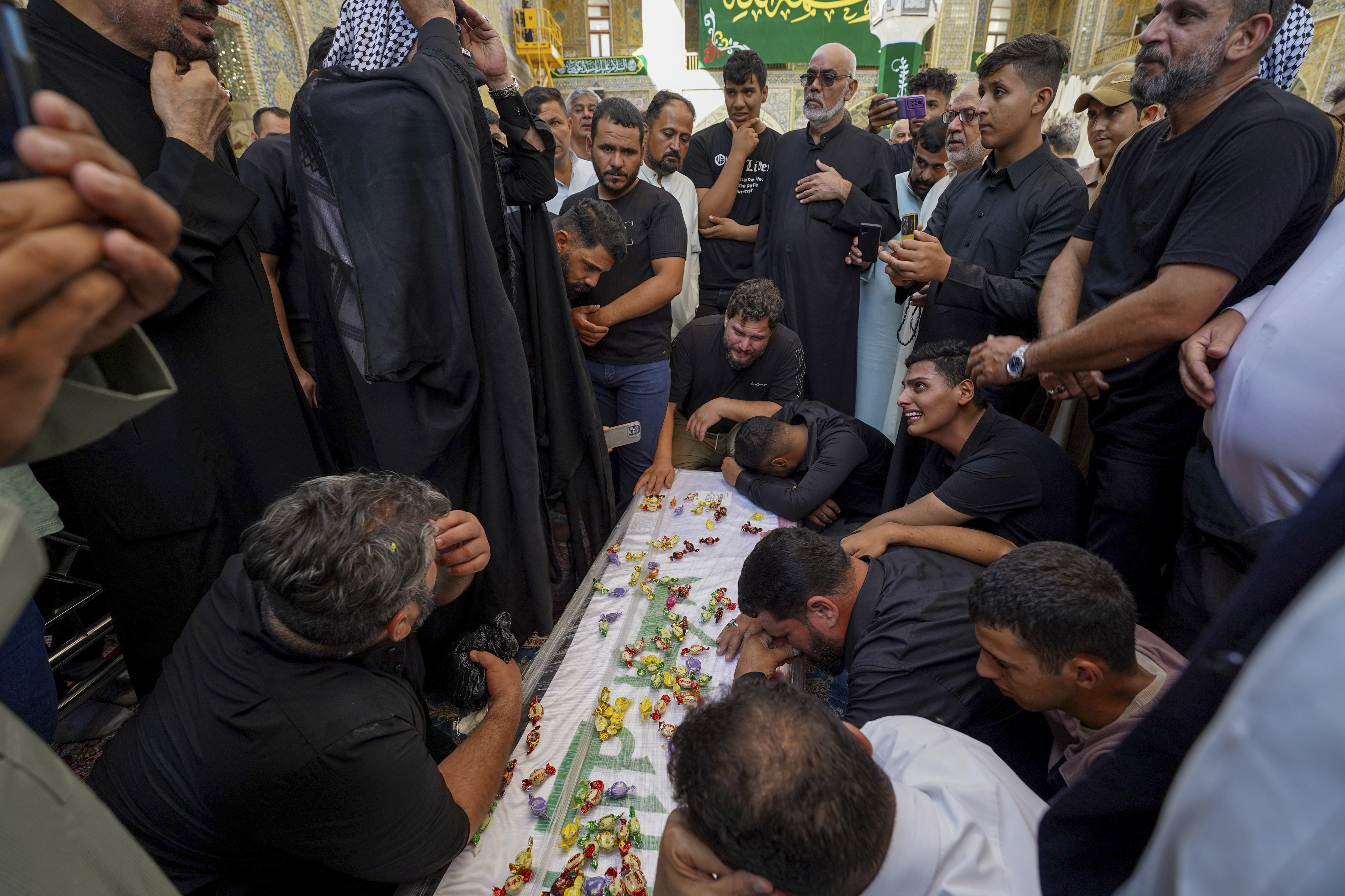 Relatives mourn over the coffin of Zulfikar Dergham Musa Al-Jabouri, in Najaf, Iraq, Thursday, Sept. 26, 2024 who died in Israeli airstrikes on Sept. 23 fighting alongside Hezbollah in Tyre, south Lebanon. (AP Photo/Anmar Khalil)