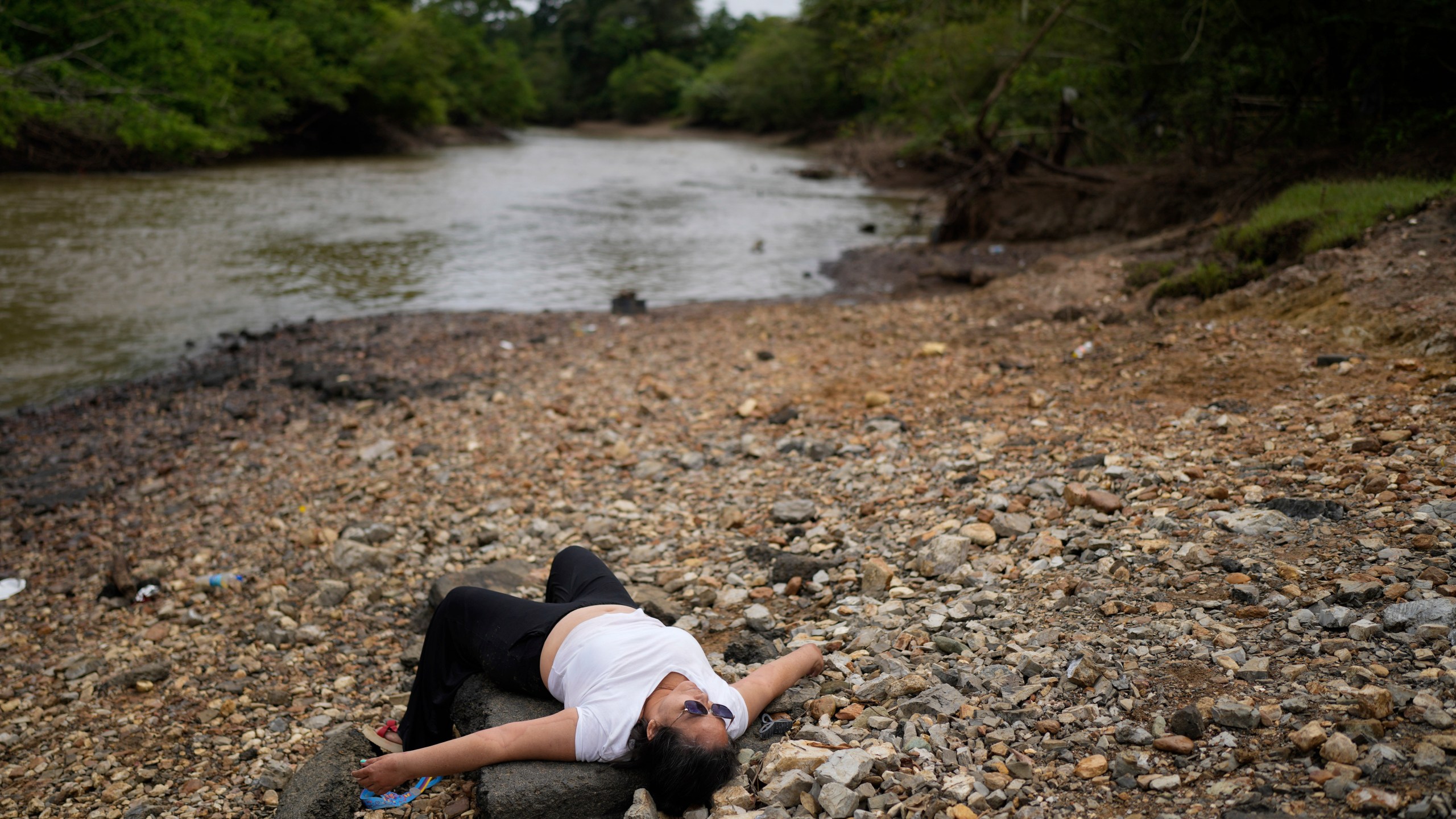 Marisol Jaime, from Venezuela, lies on the shore after disembarking from a boat in Lajas Blancas, Panama, Thursday, Sept. 26, 2024, following her trek through the Darién Gap from Colombia in hopes of reaching the U.S. (AP Photo/Matias Delacroix)