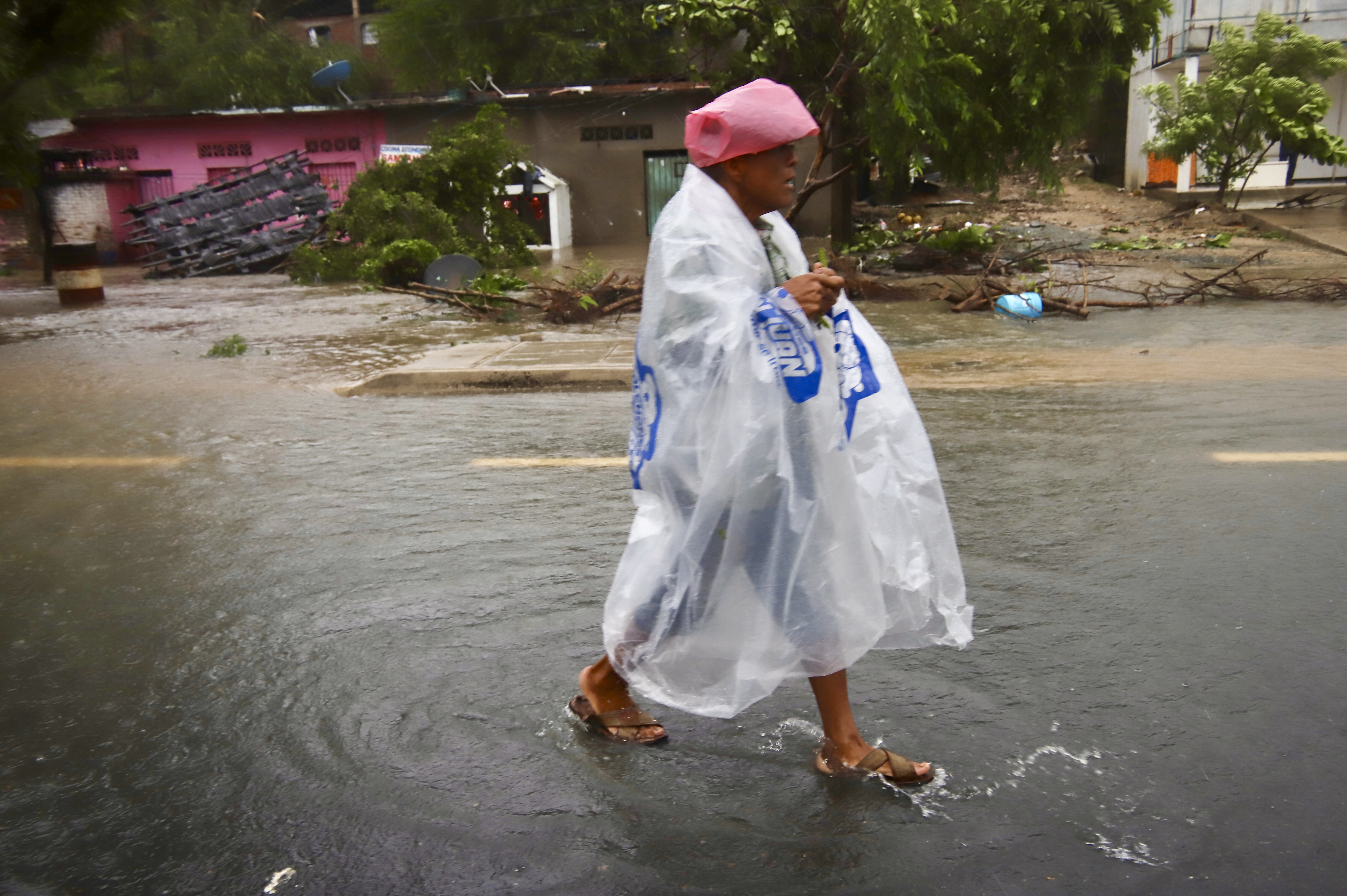 A person wearing plastic walks in the street after the passing of Hurricane John in Marquelia, Mexico, Tuesday, Sept. 24, 2024. (AP Photo/Luis Alberto Cruz)