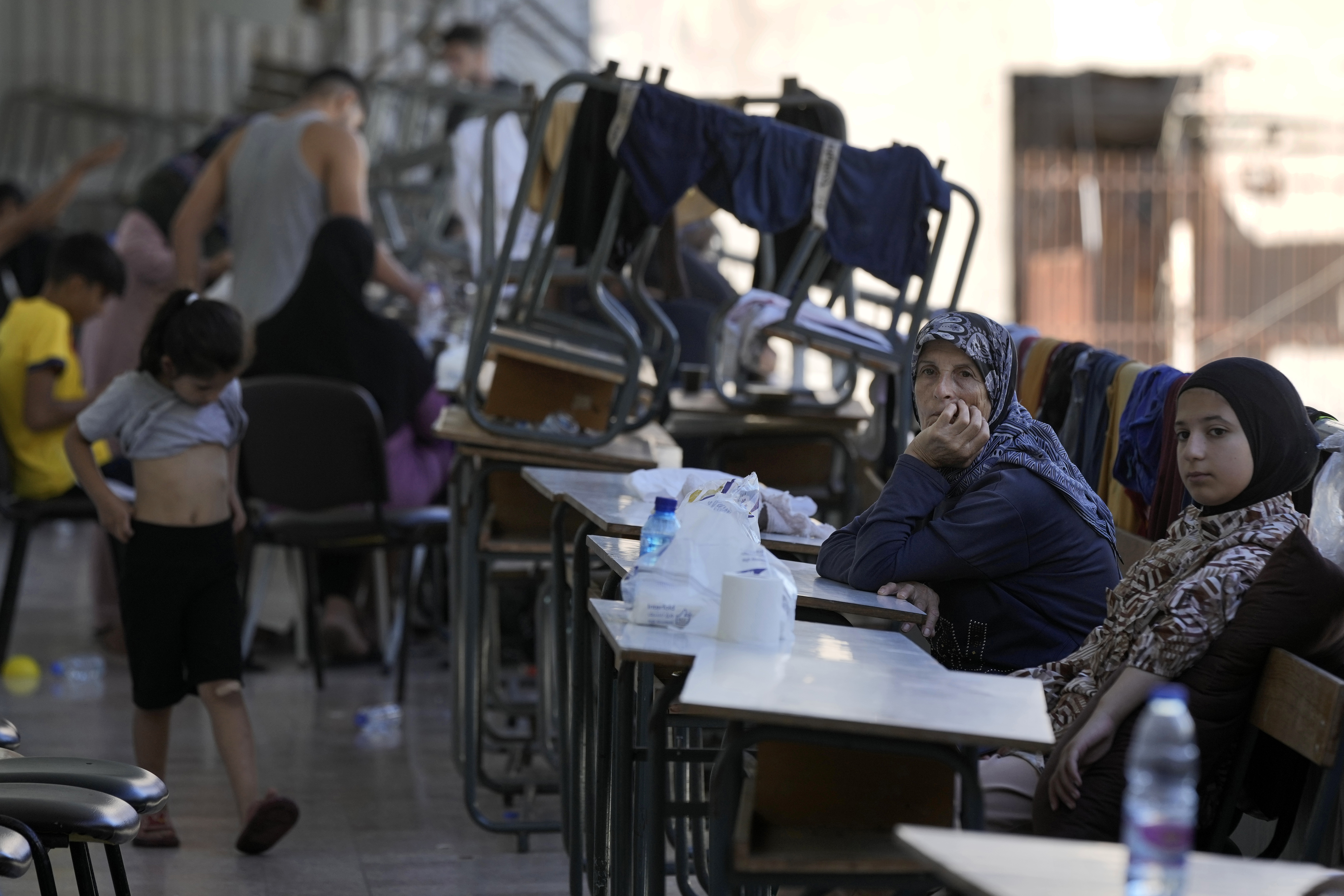 Displaced women and children sit in a classroom in Beirut, after fleeing the Israeli airstrikes in the south, Thursday, Sept. 26, 2024. (AP Photo/Bilal Hussein)