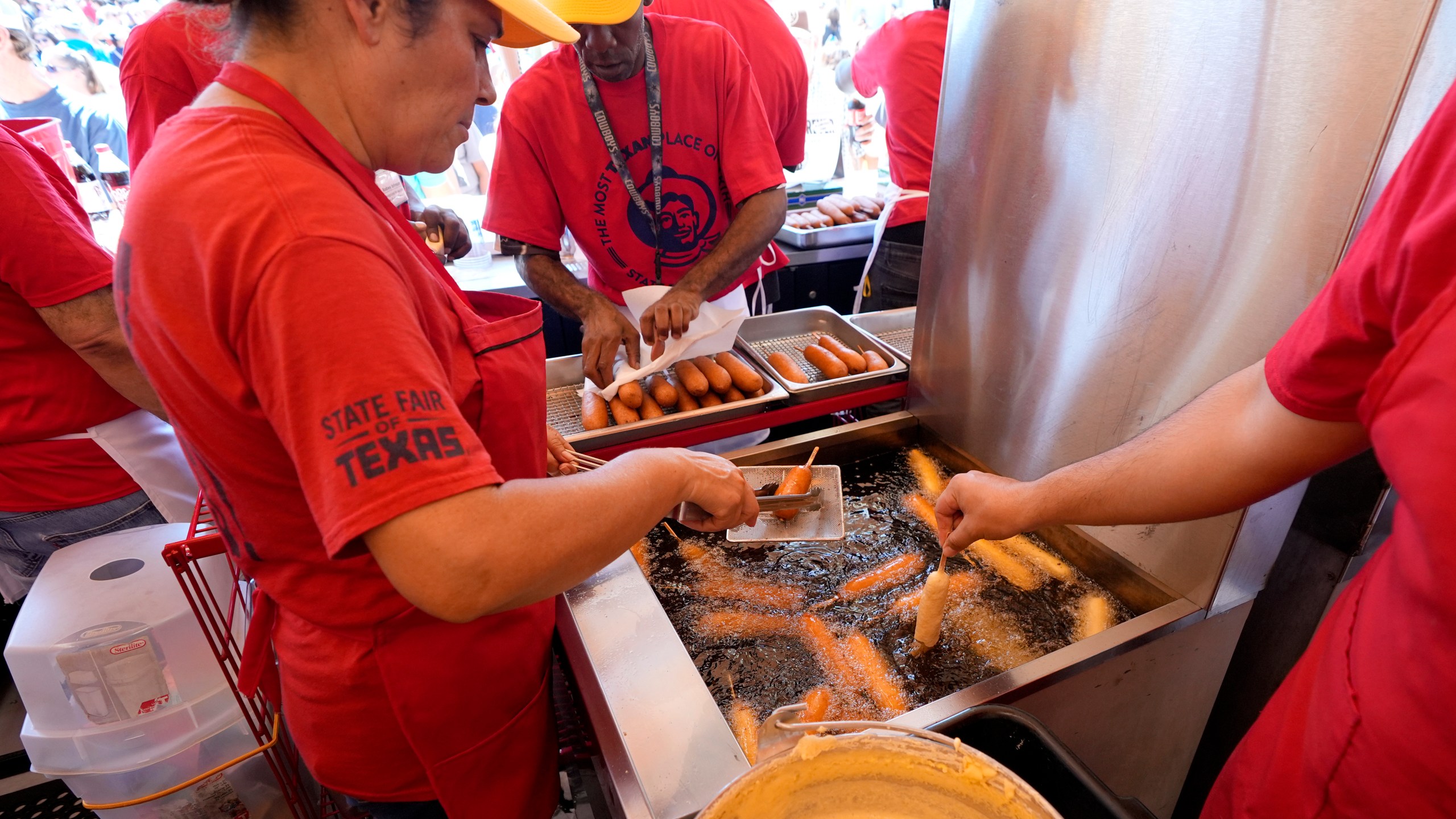 Carmen Zapata, left, helps prepare dozens of Fletchers Corny dogs at their booth at the State Fair of Texas in Dallas, Friday, Sept. 27, 2024. (AP Photo/Tony Gutierrez)