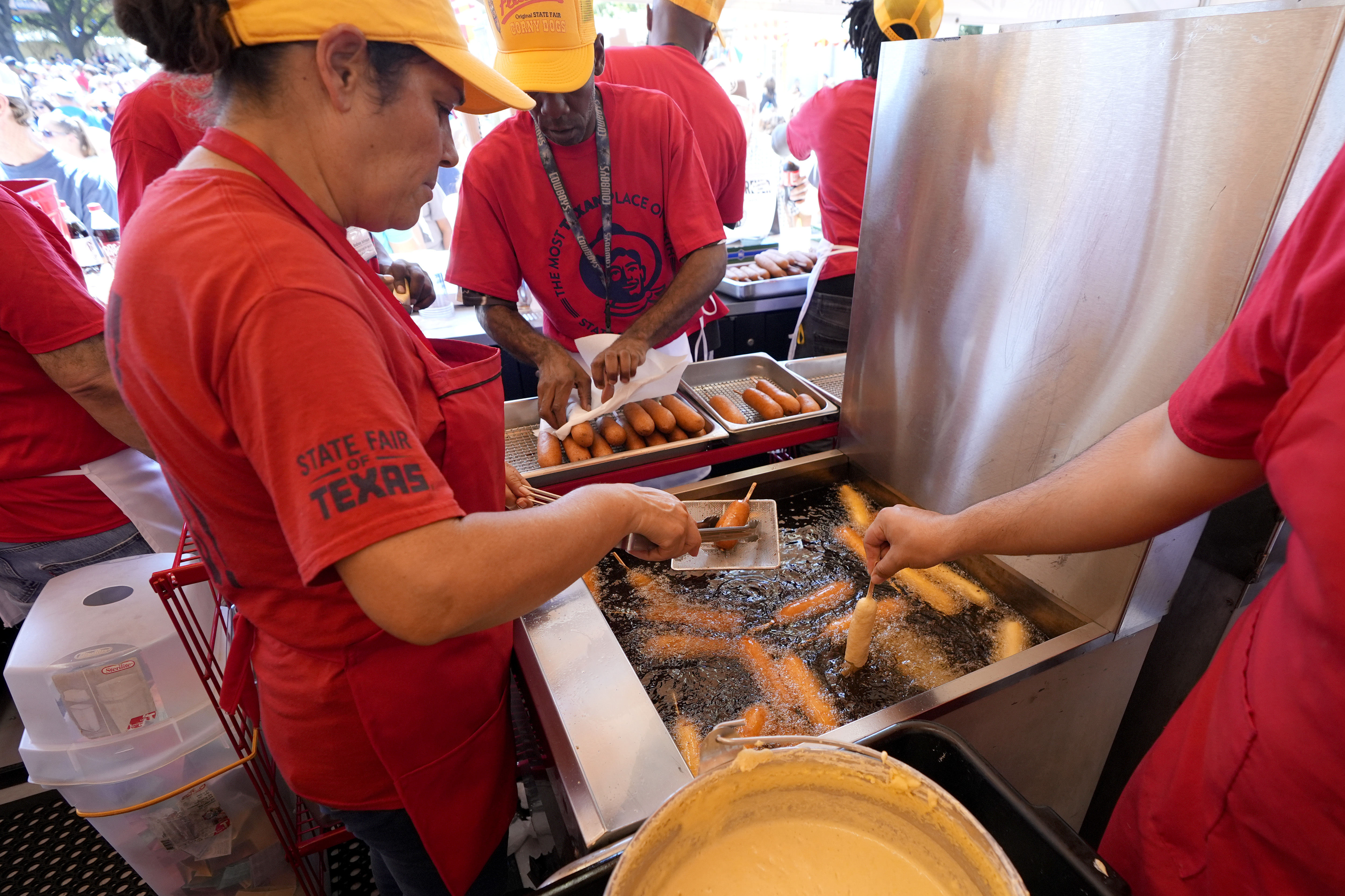 Carmen Zapata, left, helps prepare dozens of Fletchers Corny dogs at their booth at the State Fair of Texas in Dallas, Friday, Sept. 27, 2024. (AP Photo/Tony Gutierrez)