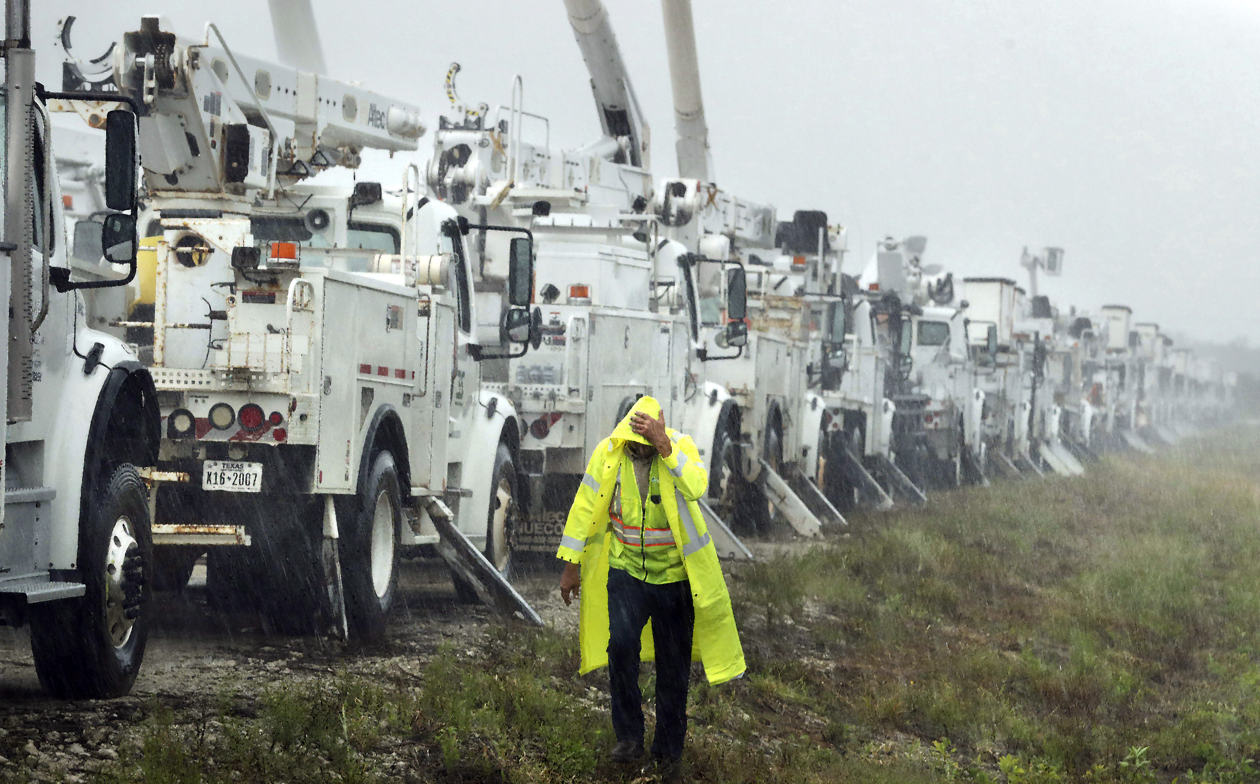 Charles Starling, a lineman with Team Fishel, is pelted with rain as he walks by a row of electrical line trucks stage in a field in The Villages, Fla., Thursday, Sept. 26, 2024, in preparation for damage from Hurricane Helene. (Stephen M. Dowell/Orlando Sentinel via AP)