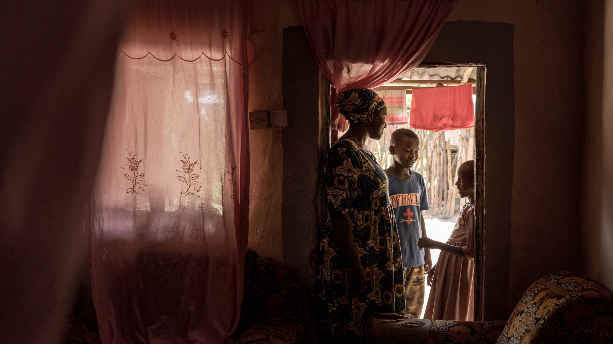 Musukebbe Manjang, left, speaks with her son Boubacar Darbo, center, and his sister Fatima in the village of Kwinella, Gambia, on July 27, 2024. (AP Photo/Annika Hammerschlag)