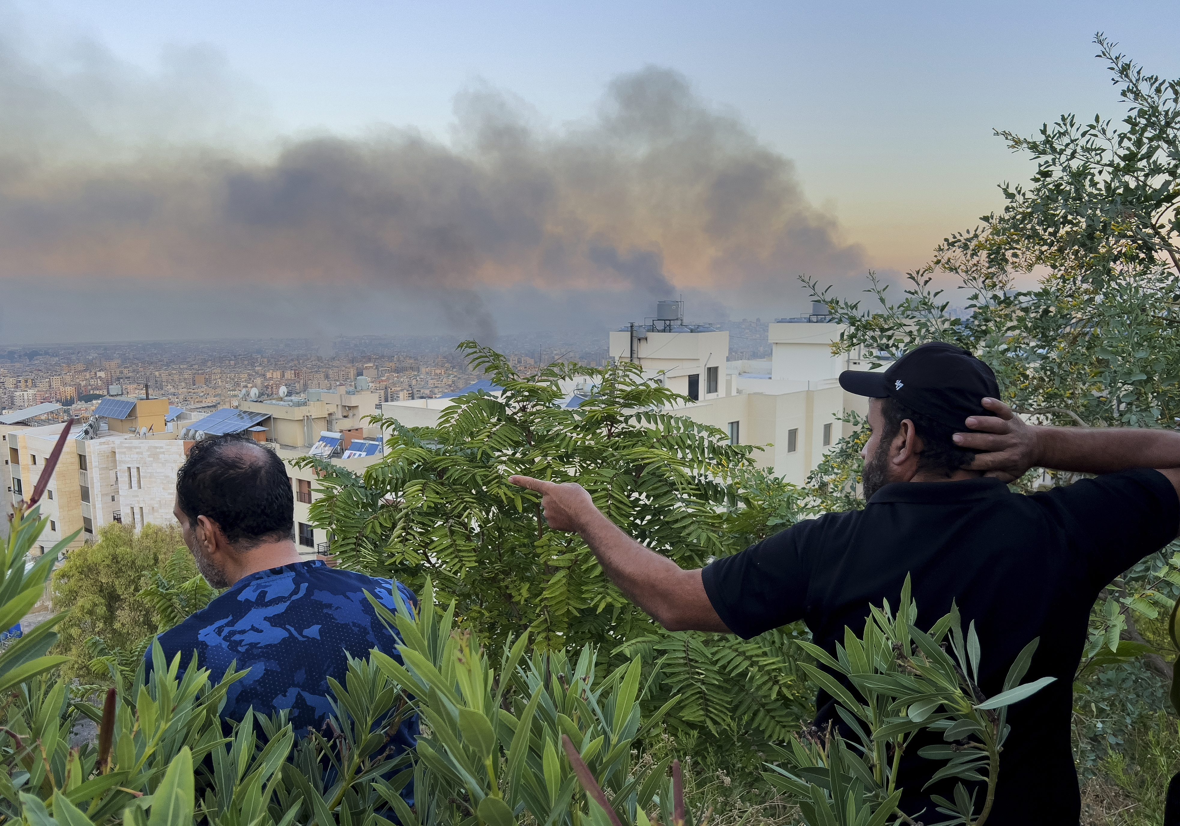 Lebanese citizens watch smoke rise from Israeli airstrikes in the southern suburbs of Beirut, Lebanon, Saturday, Sept. 28, 2024. (AP Photo/Hussein Malla)