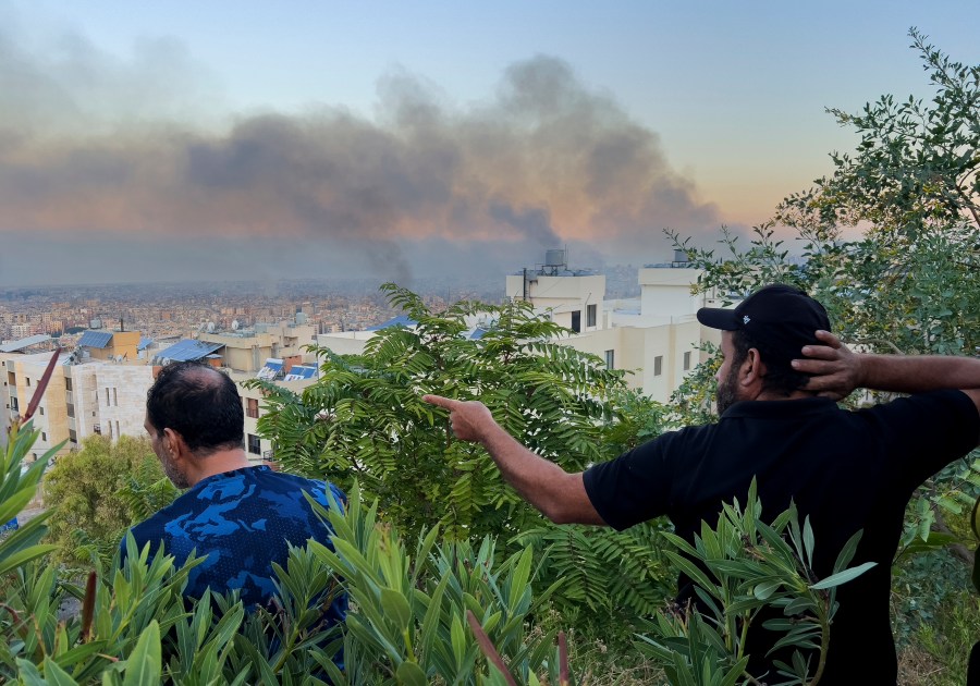 Lebanese citizens watch smoke rise from Israeli airstrikes in the southern suburbs of Beirut, Lebanon, Saturday, Sept. 28, 2024. (AP Photo/Hussein Malla)