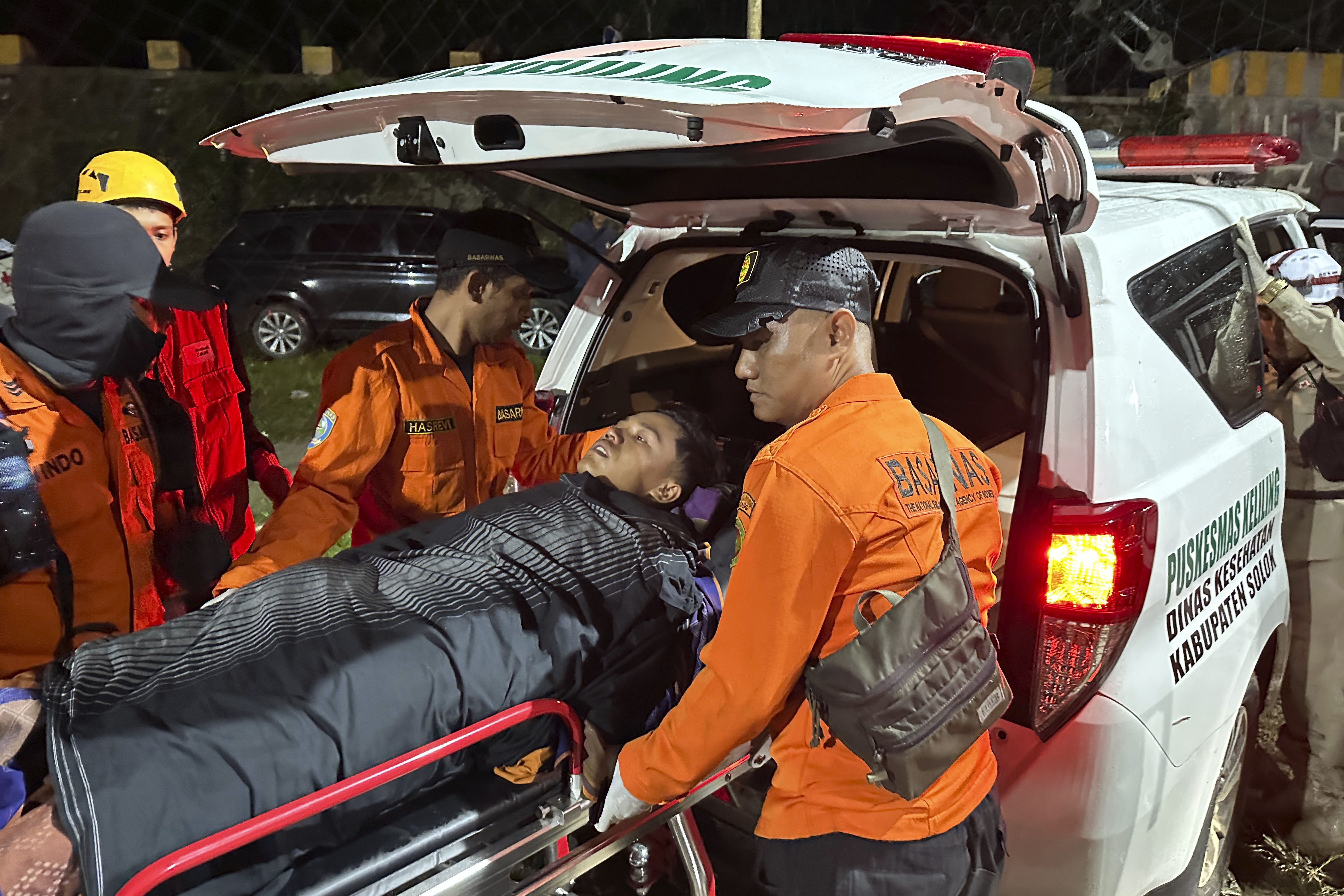 Rescuers transfer a survivor into an ambulance after a landslide set off by torrential rains smashed down into an unauthorized gold mining operation, killing several people, in Solok, West Sumatra, Indonesia, Saturday, Sept. 28, 2024. (AP Photo/John Nedy)