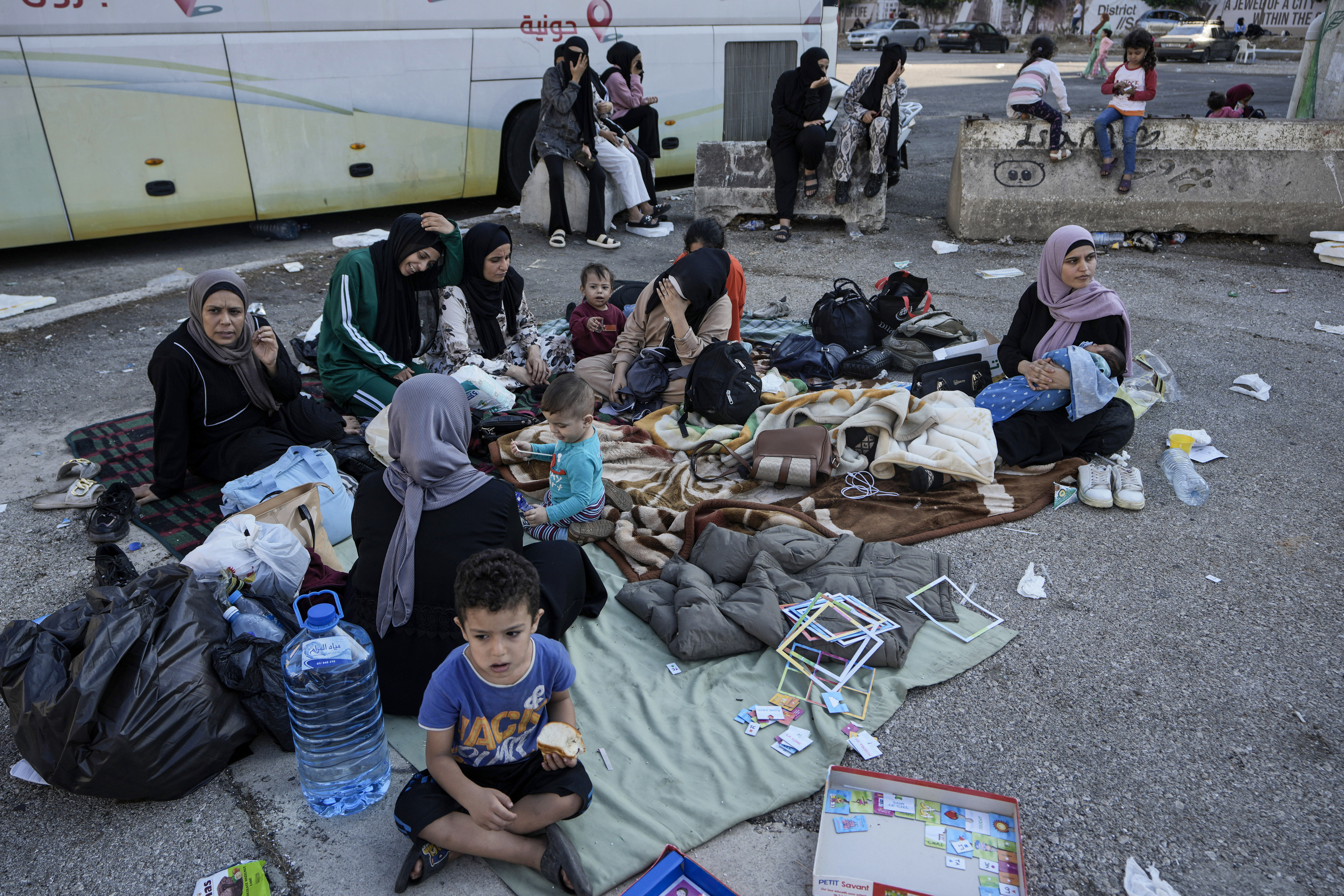 Families sit on the ground in Martyrs' square after fleeing the Israeli airstrikes in Beirut's southern suburbs, Saturday, Sept. 28, 2024. (AP Photo/Bilal Hussein)