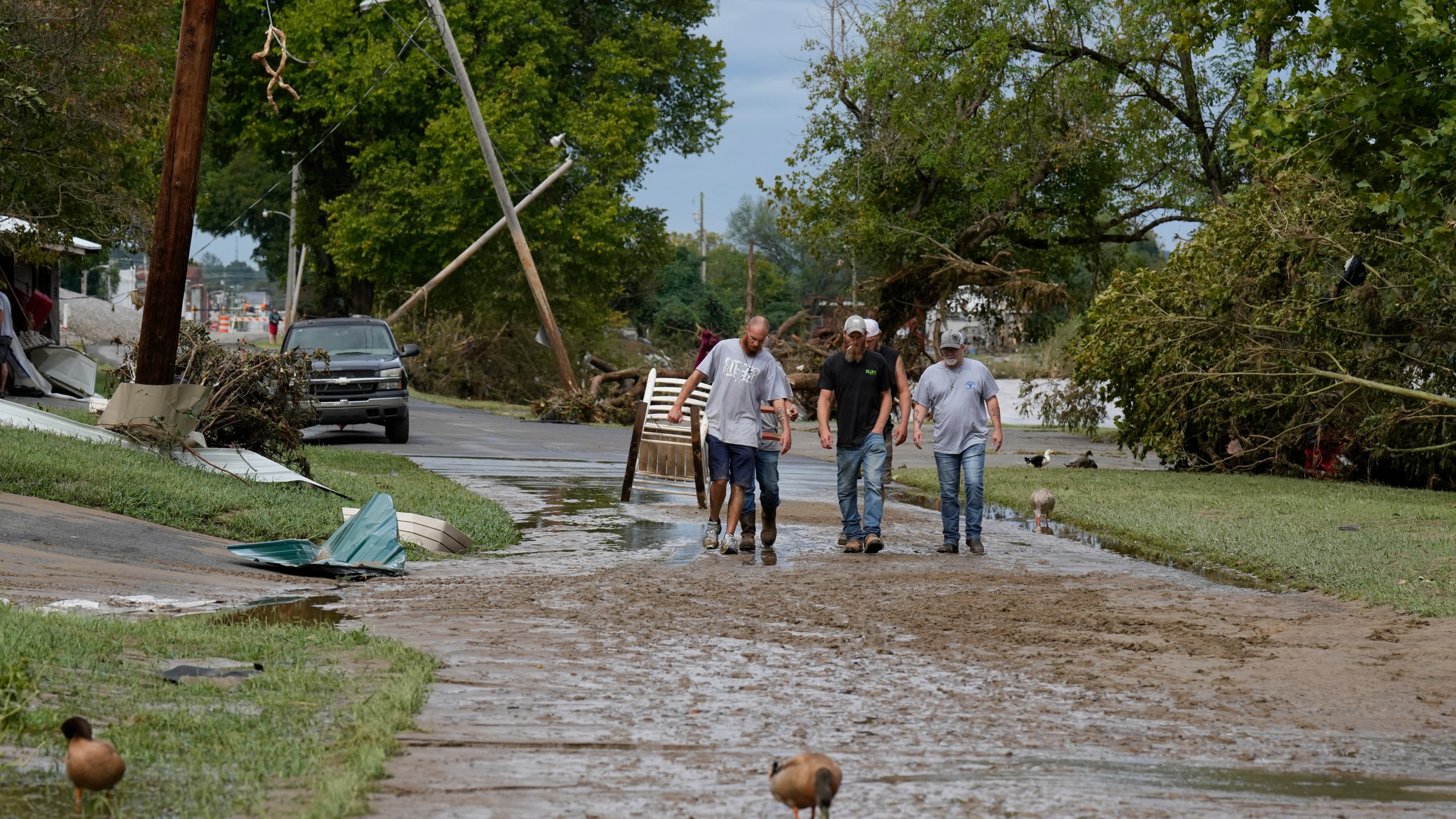 People walk along River St. flood damage is seen Saturday, Sept. 28, 2024, in Newport, Tenn. (AP Photo/George Walker IV)