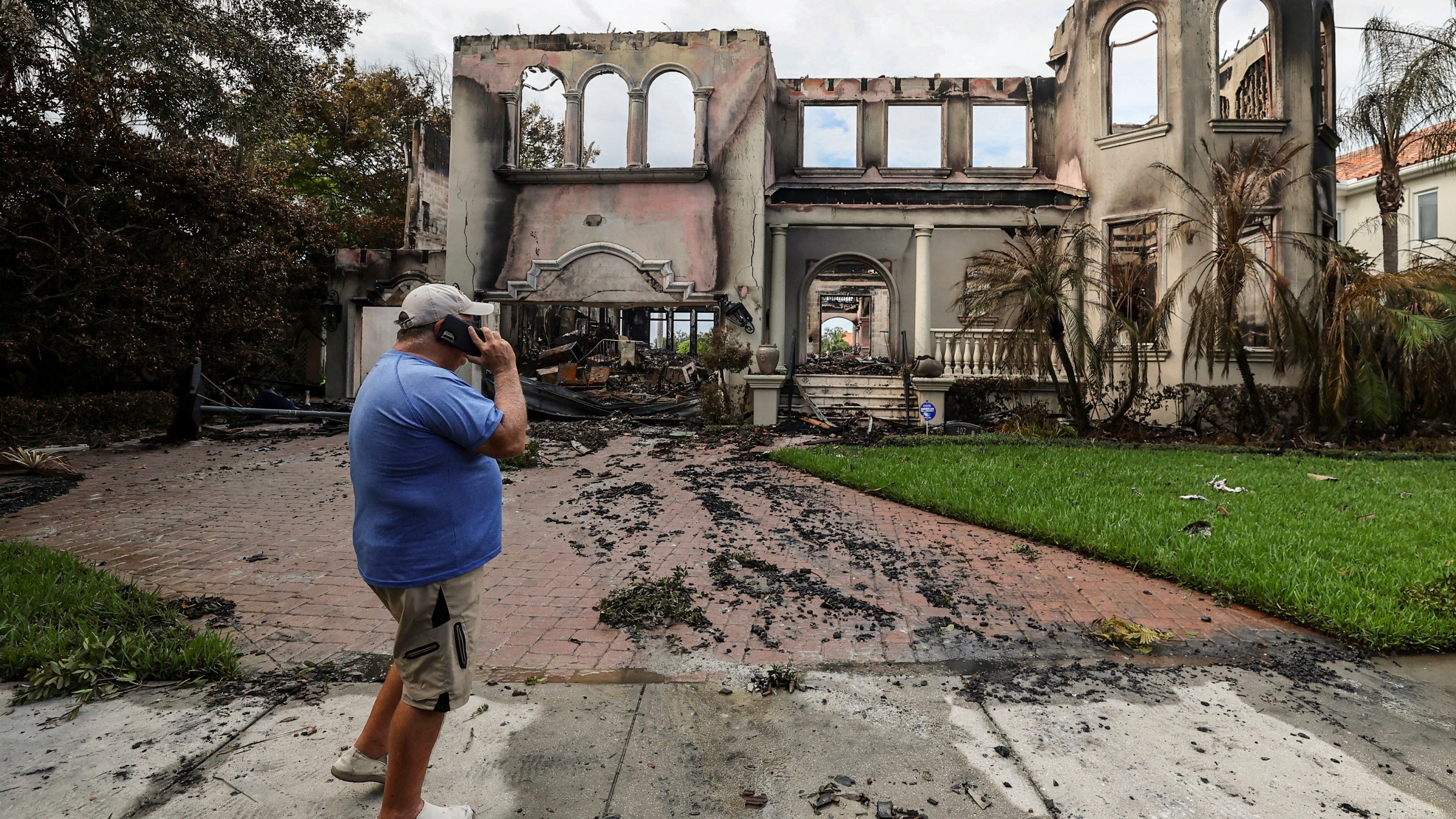 Joe Daum looks at the remains of a friend's home that burned during Hurricane Helene on Davis Island Saturday, Sept. 28, 2024, in Tampa, Fla. (AP Photo/Mike Carlson)