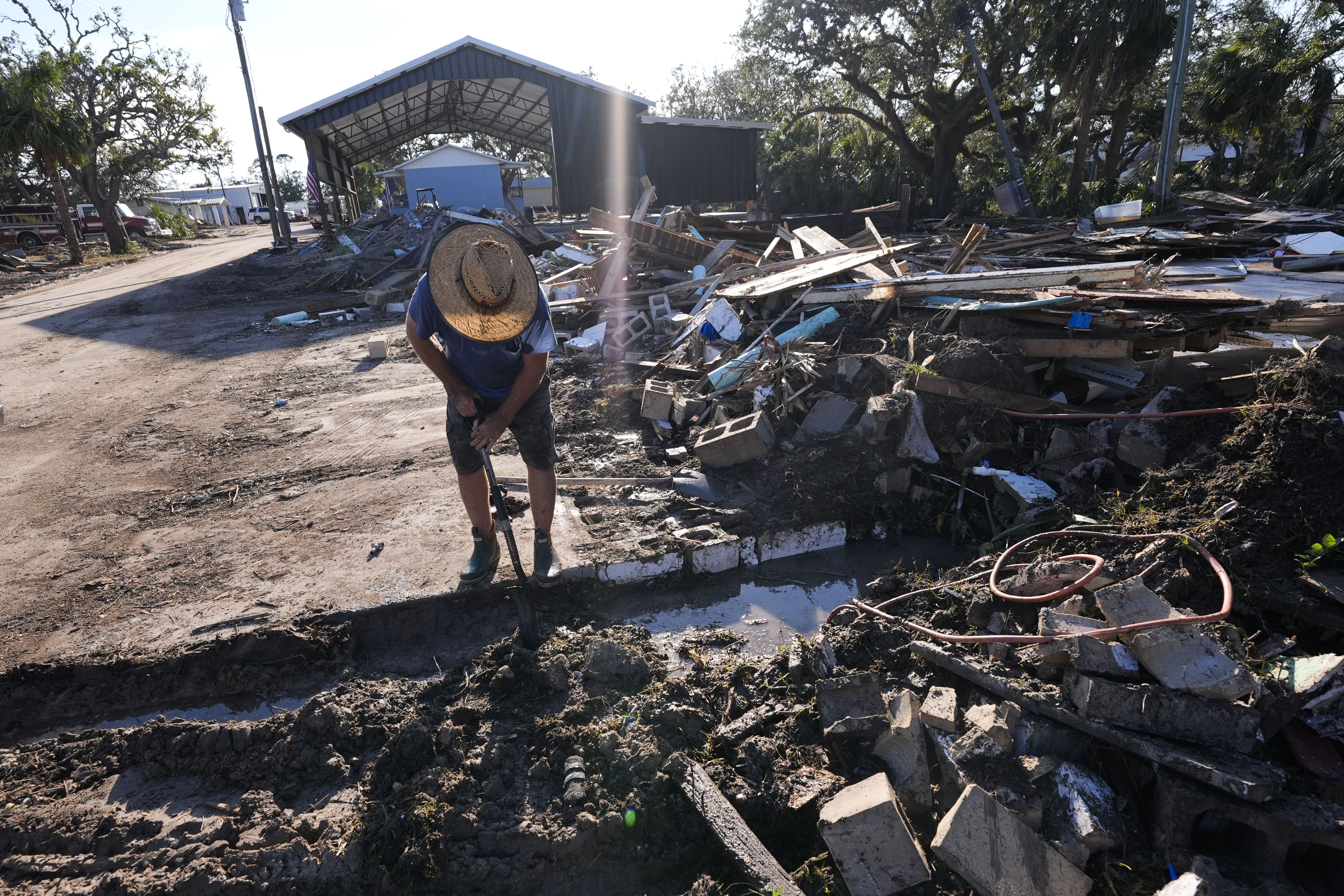 Chris Jordan, maintenance manager for Horseshoe Beach, tries to find a water shutoff valve amid the rubble of the destroyed city hall in the aftermath of Hurricane Helene, in Horseshoe Beach, Fla., Sunday, Sept. 29, 2024. (AP Photo/Gerald Herbert)