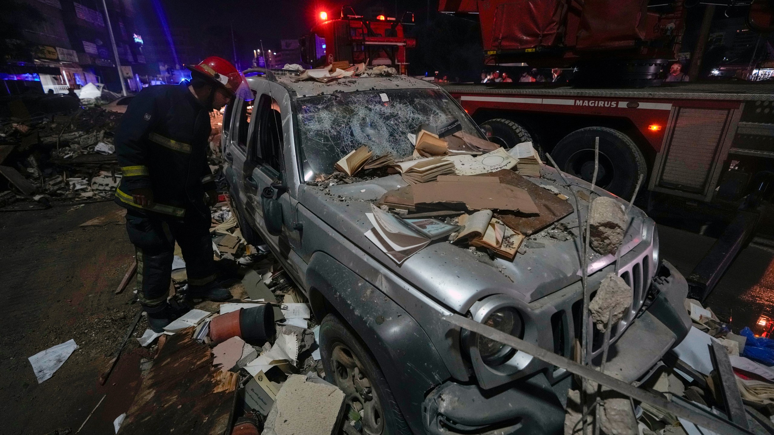 A firefighter inspects a damaged car near a building that was hit in an Israeli airstrike, in Beirut, Lebanon, early Monday, Sept. 30, 2024. (AP Photo/Bilal Hussein)