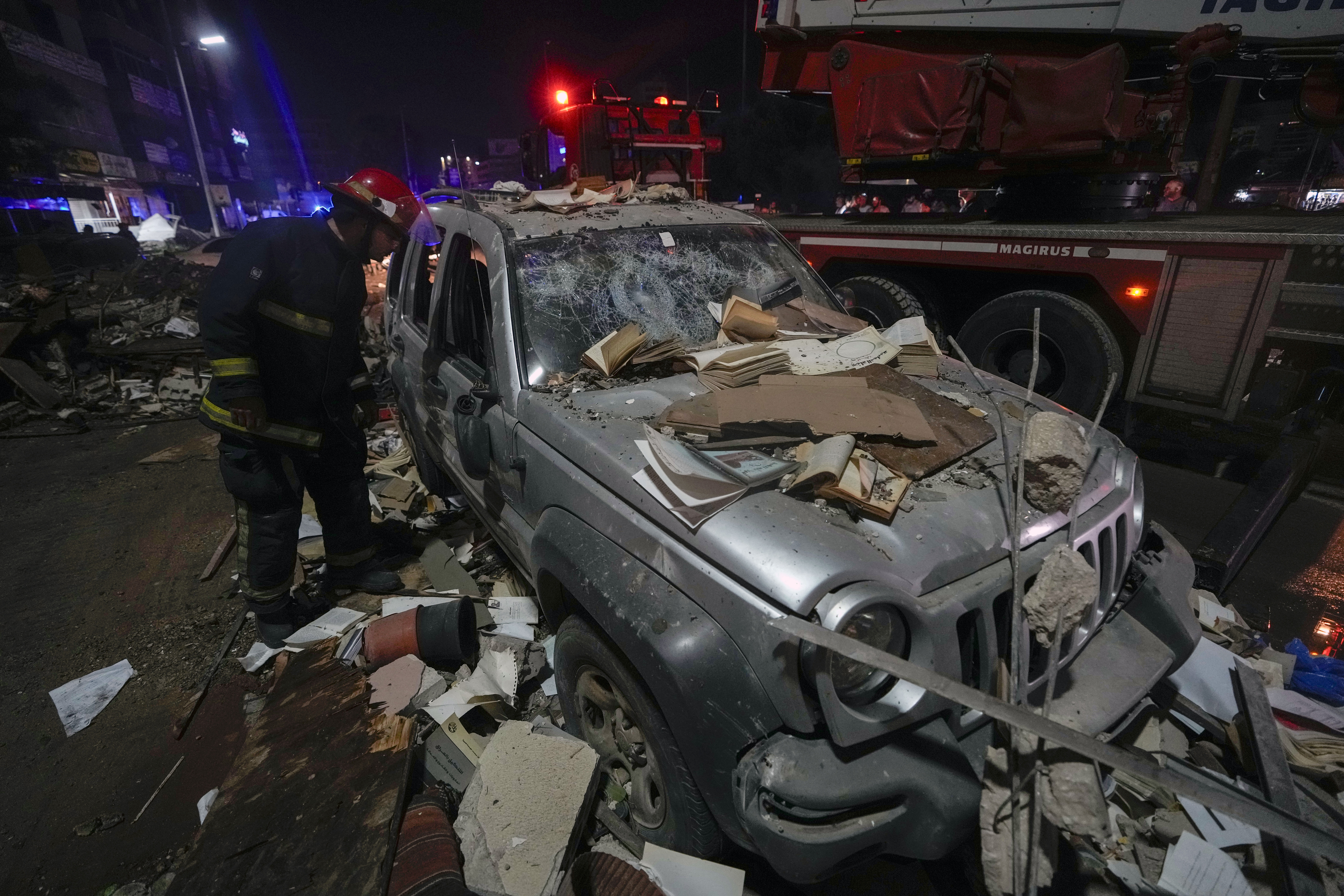 A firefighter inspects a damaged car near a building that was hit in an Israeli airstrike, in Beirut, Lebanon, early Monday, Sept. 30, 2024. (AP Photo/Bilal Hussein)