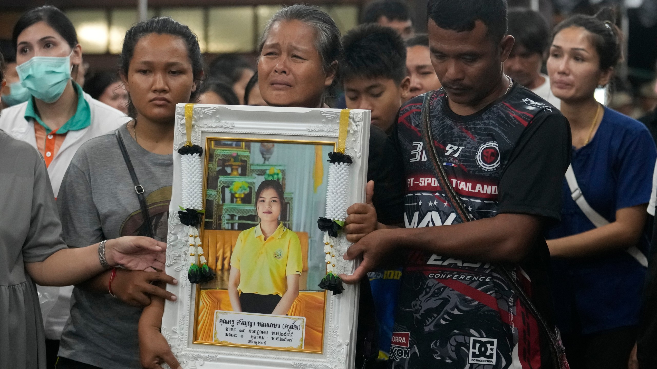 Victims' relatives carry portraits of the victims of a bus fire in a procession at Wat Khao Phraya Sangkharam School Lan Sak, Uthai Thani province, Thailand, Thursday, Oct. 3, 2024. (AP Photo/Sakchai Lalit)