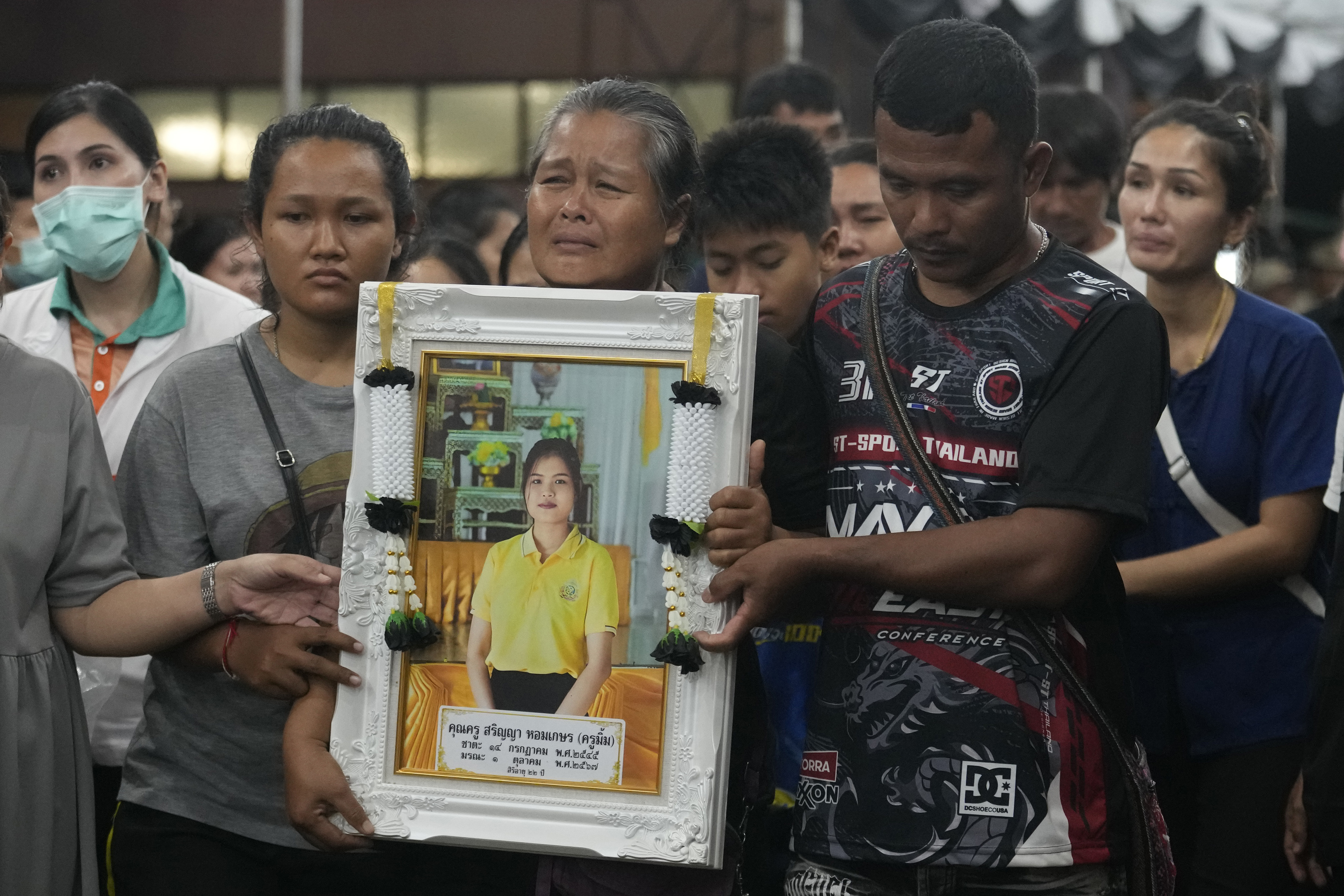 Victims' relatives carry portraits of the victims of a bus fire in a procession at Wat Khao Phraya Sangkharam School Lan Sak, Uthai Thani province, Thailand, Thursday, Oct. 3, 2024. (AP Photo/Sakchai Lalit)