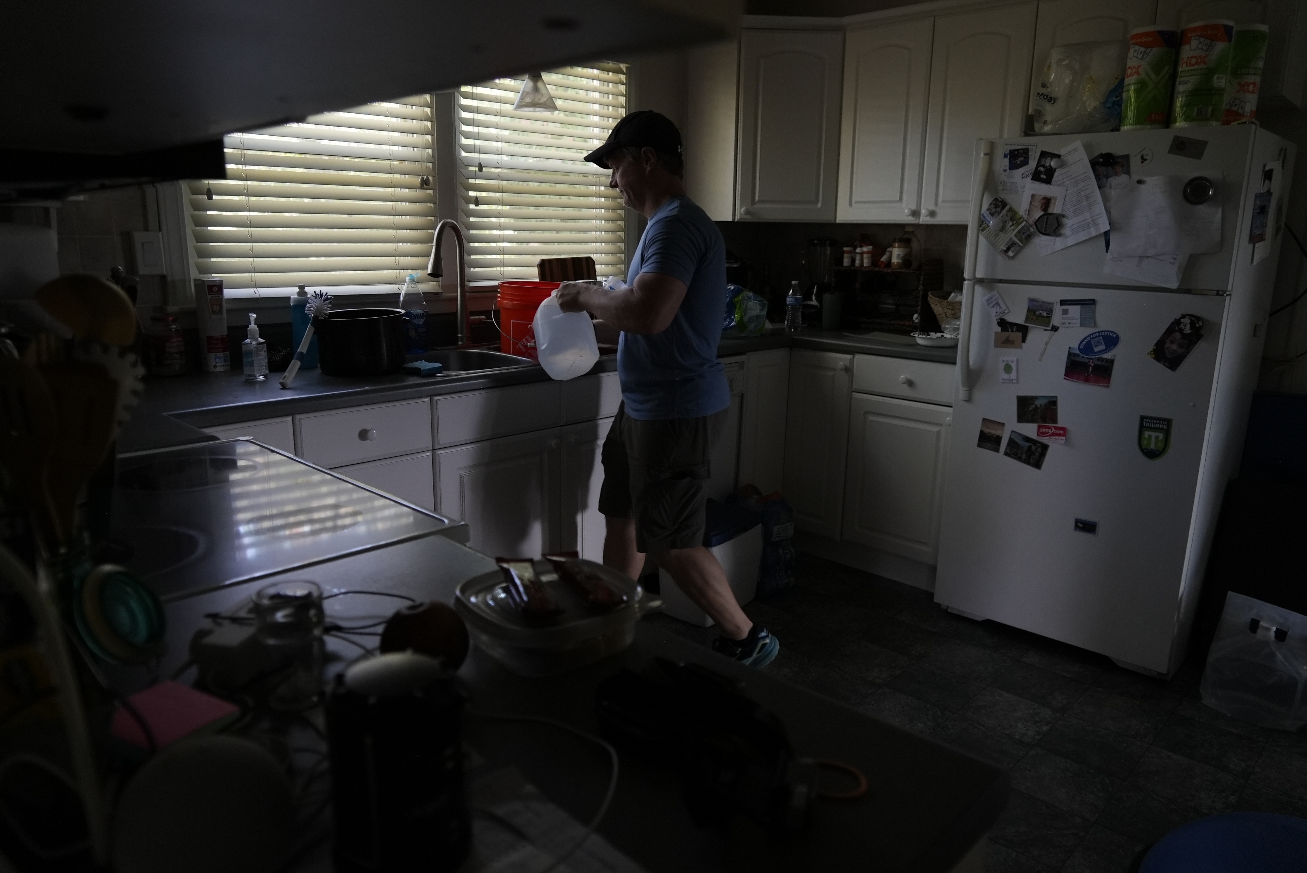 Travis Edwards organizes his drinking water supply Thursday, Oct. 3, 2024 in Asheville, North Carolina. He hasn't had water since Hurricane Helene struck the area, and reuses water to flush toilets. (AP Photo/Brittany Peterson)