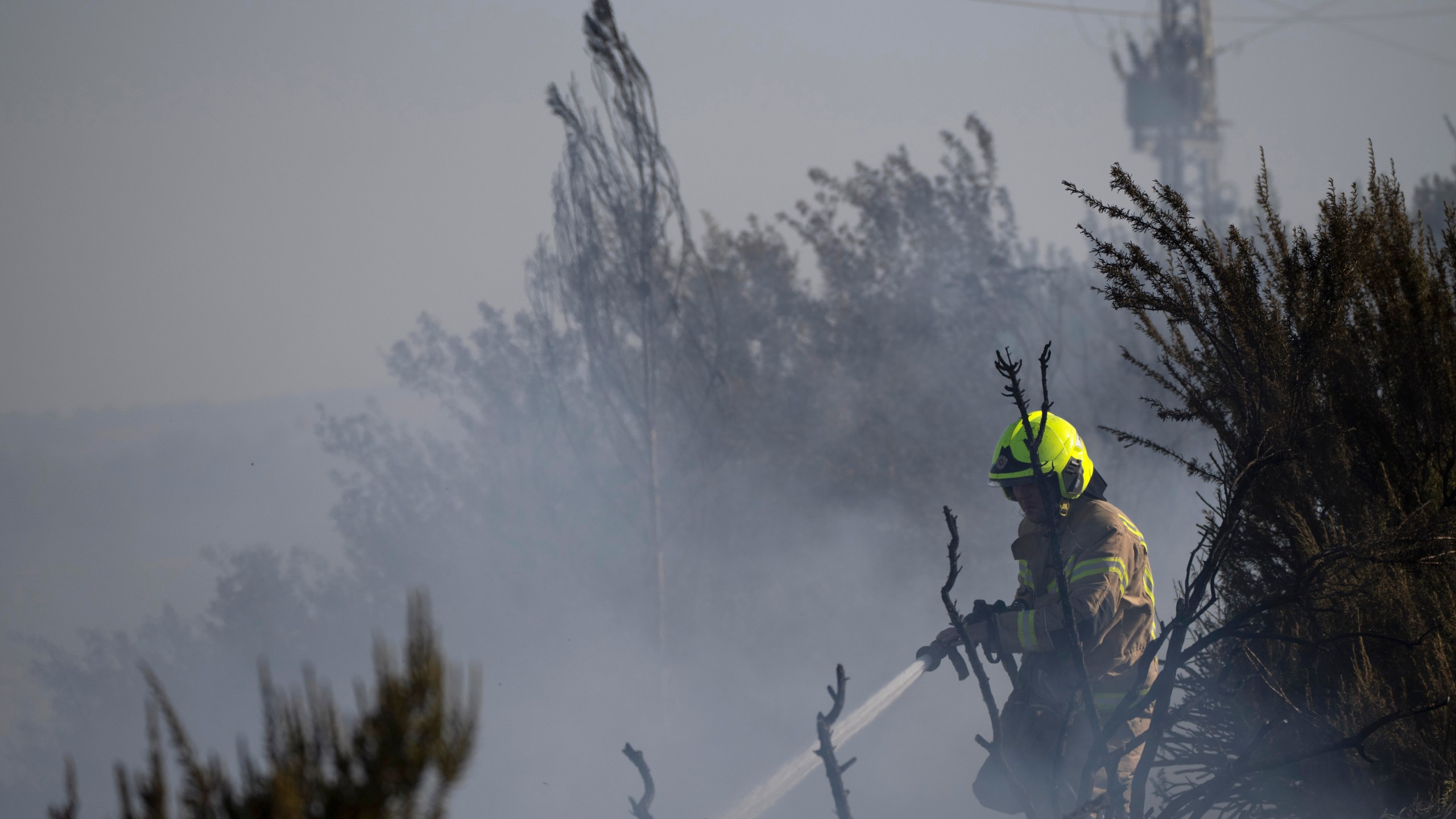 A firefighter works to extinguish a fire after a rocket, fired from Lebanon, hit an area next to a road near Kiryat Shmona, northern Israel, Saturday, Oct. 5, 2024. (AP Photo/Leo Correa)