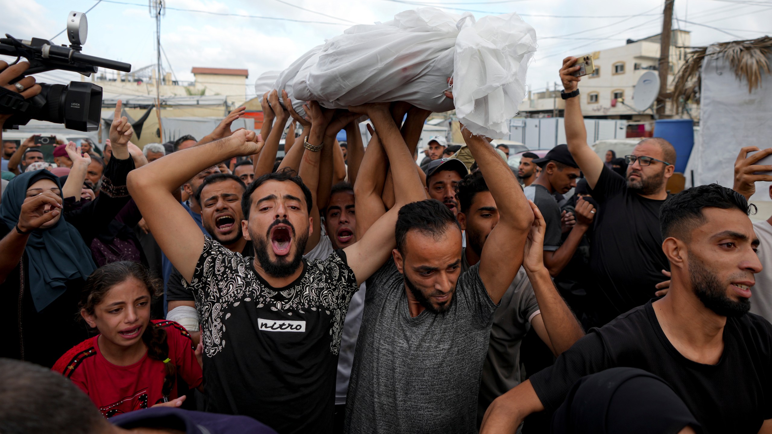 Palestinians mourn as they carry the body of a relative killed in the Israeli bombardment of the Gaza Strip at a hospital in Deir al-Balah, Tuesday, Oct. 8, 2024. (AP Photo/Abdel Kareem Hana)