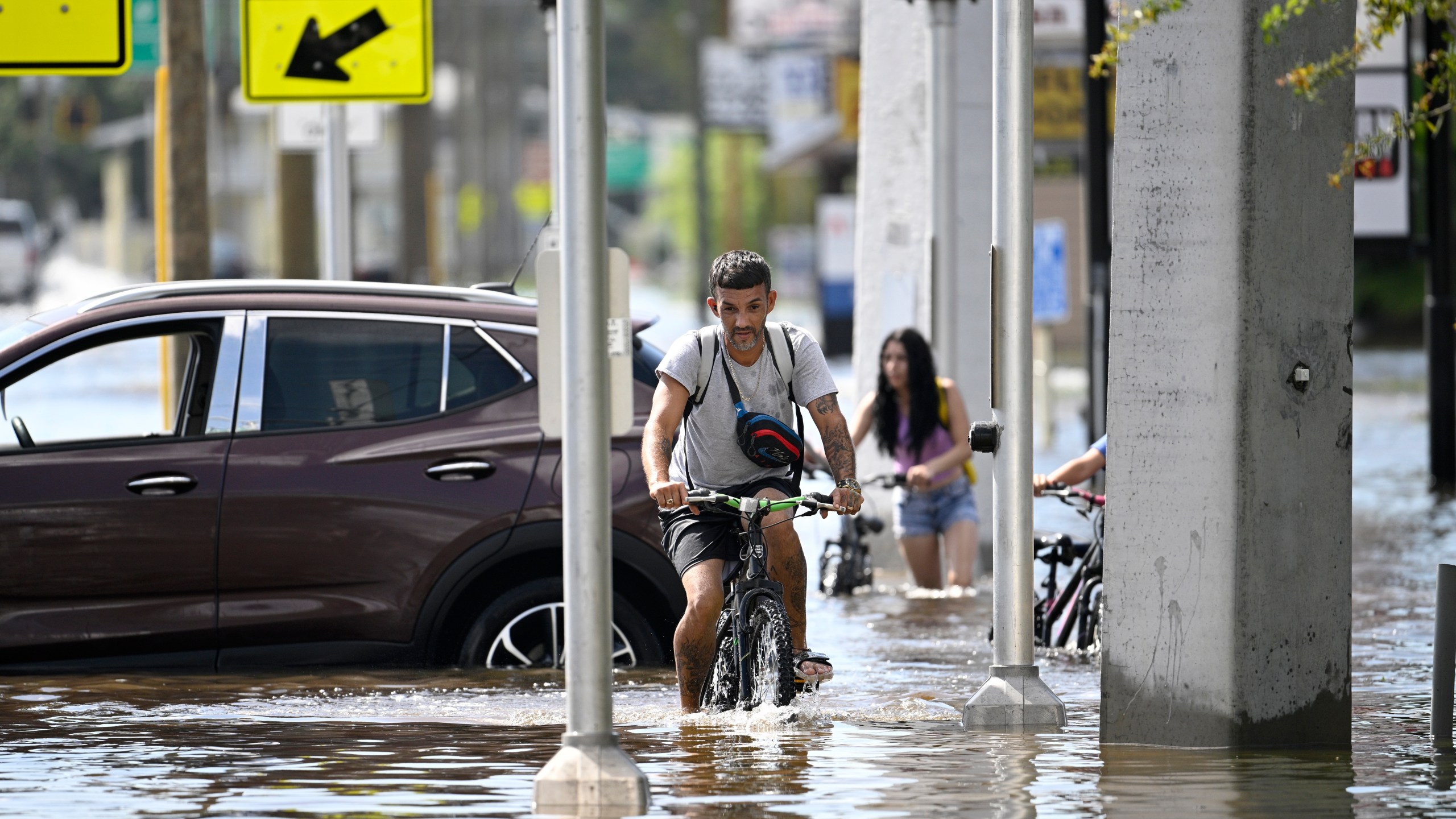 FILE - Mica Martell, left, and his niece and nephews ride bicycles through a flooded neighborhood, Sept. 27, 2024, in Crystal River, Fla. (AP Photo/Phelan M. Ebenhack, File)