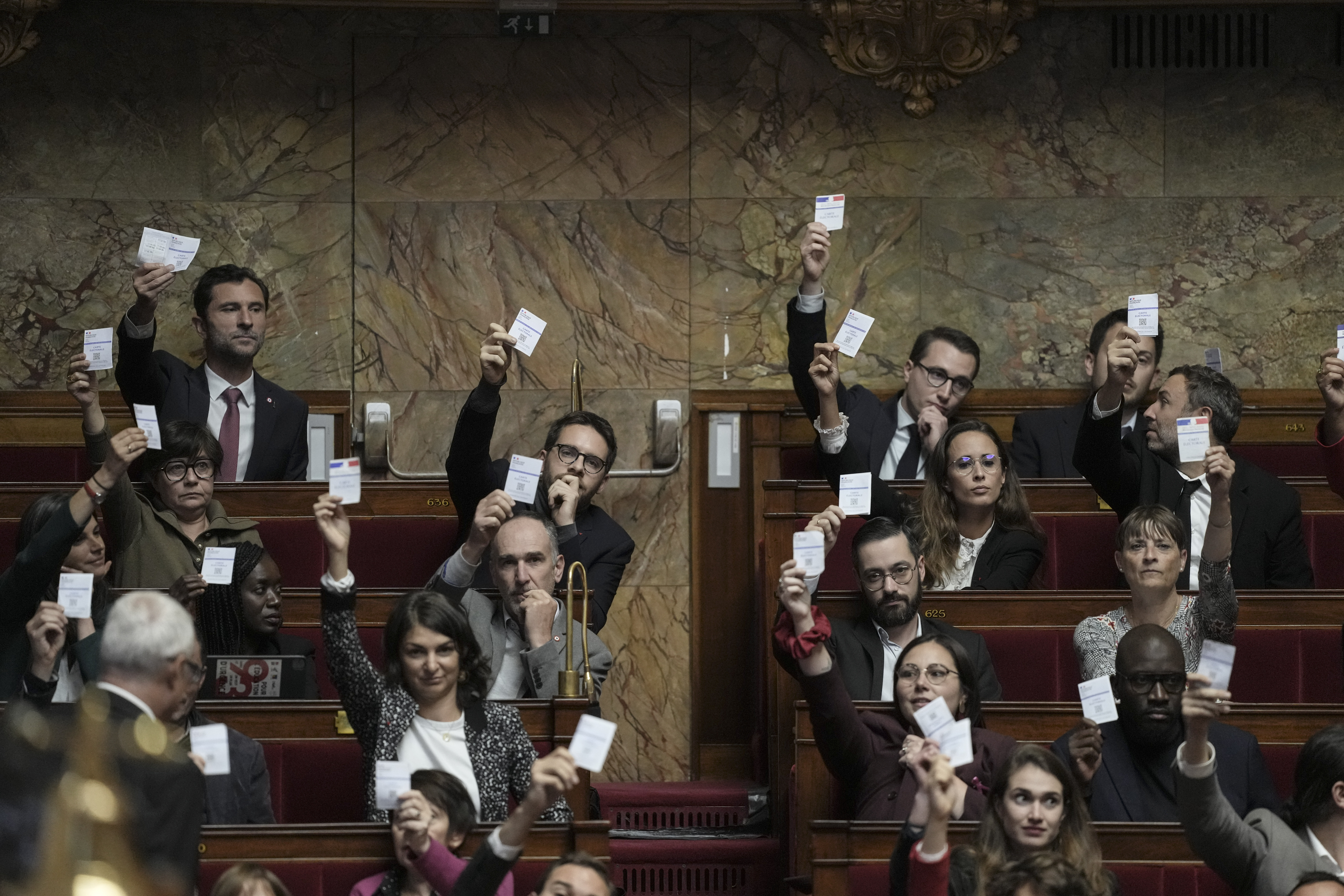 Members of the French unbowed party show their voting cards during the speech Prime Minister Michel Barnier arrives at the National Assembly, in Paris, Tuesday, Oct. 1, 2024. (AP Photo/Thibault Camus)