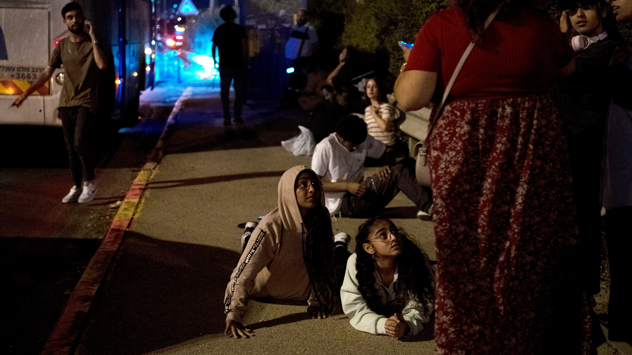 FILE - Israelis wait to re-board their bus after projectiles were launched from Iran are being intercepted in the skies over in Rosh HaAyin, Israel, Tuesday, Oct. 1, 2024. (AP Photo/Maya Alleruzzo, File)